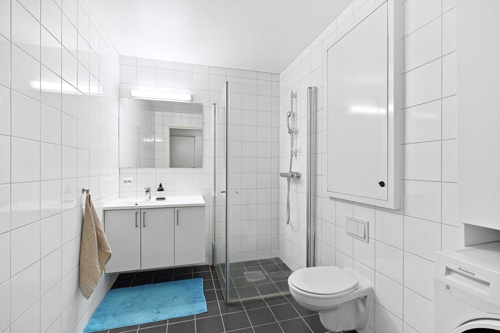 Helfliset baderom med moderne innredning, dusjhjørne og vegghengt toalett. Galleribilde