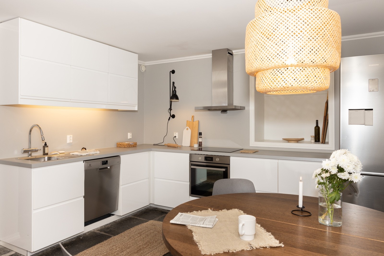 Kjøkkeninnredningen har glatte hvite fronter med innfelte håndtak. I kombinasjon med en mørkere benkeplate i laminat er dette et tidløst kjøkken. Galleribilde