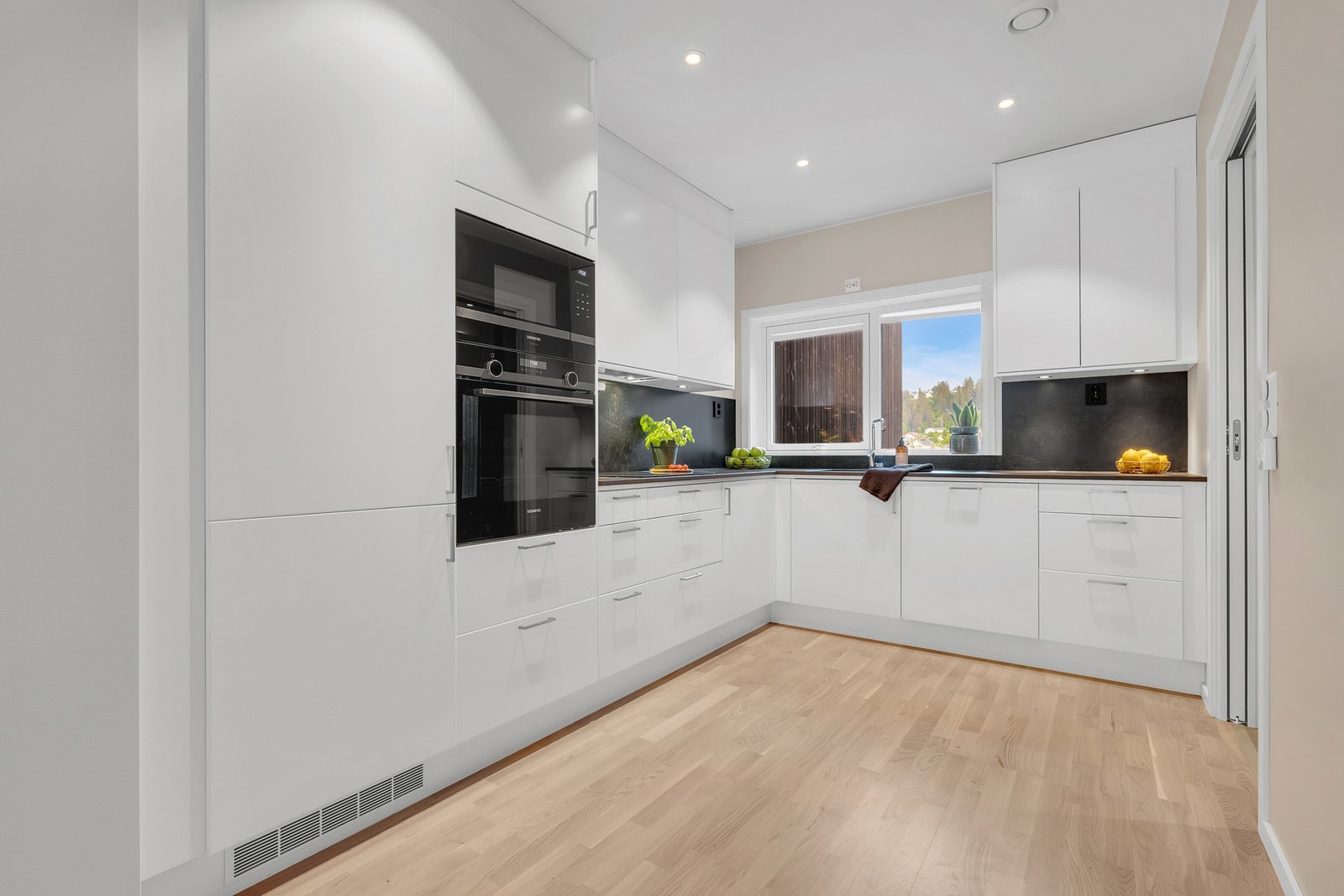 Lekkert kjøkken fra Drømmekjøkkenet med integrerte hvitevarer, eksklusiv Dekton benkeplate og mye skapplass. Galleribilde