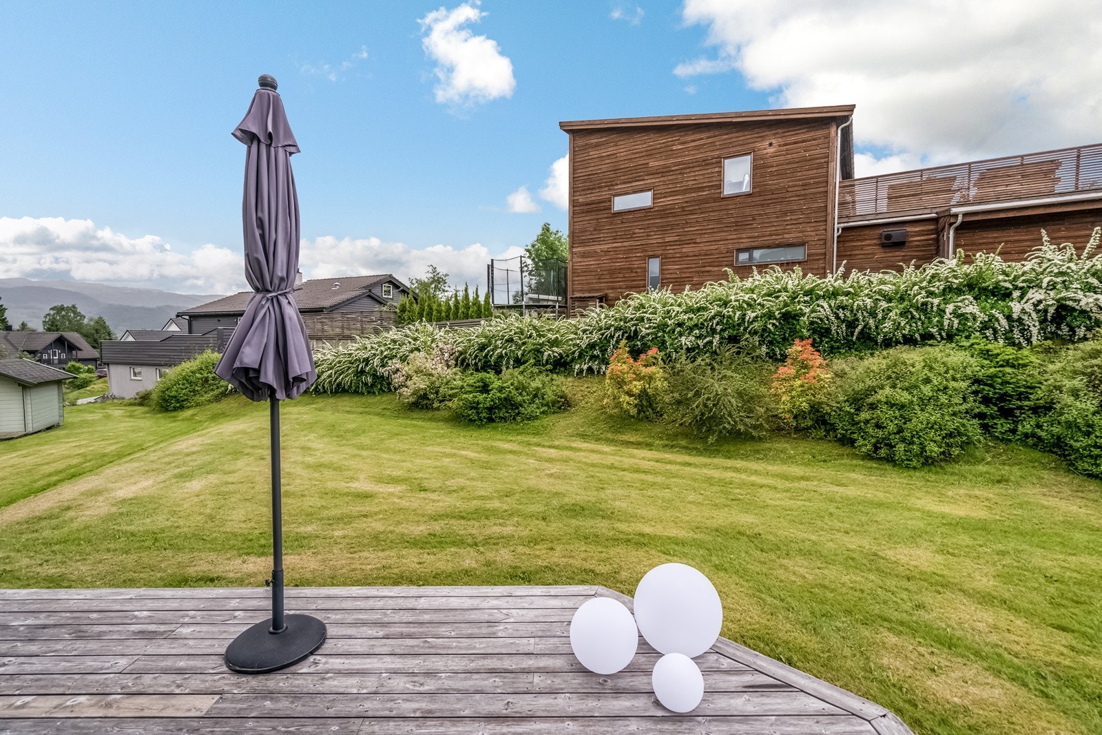 Trapp ned til terrasseplatting på bakkeplan i tre og plen. Galleribilde