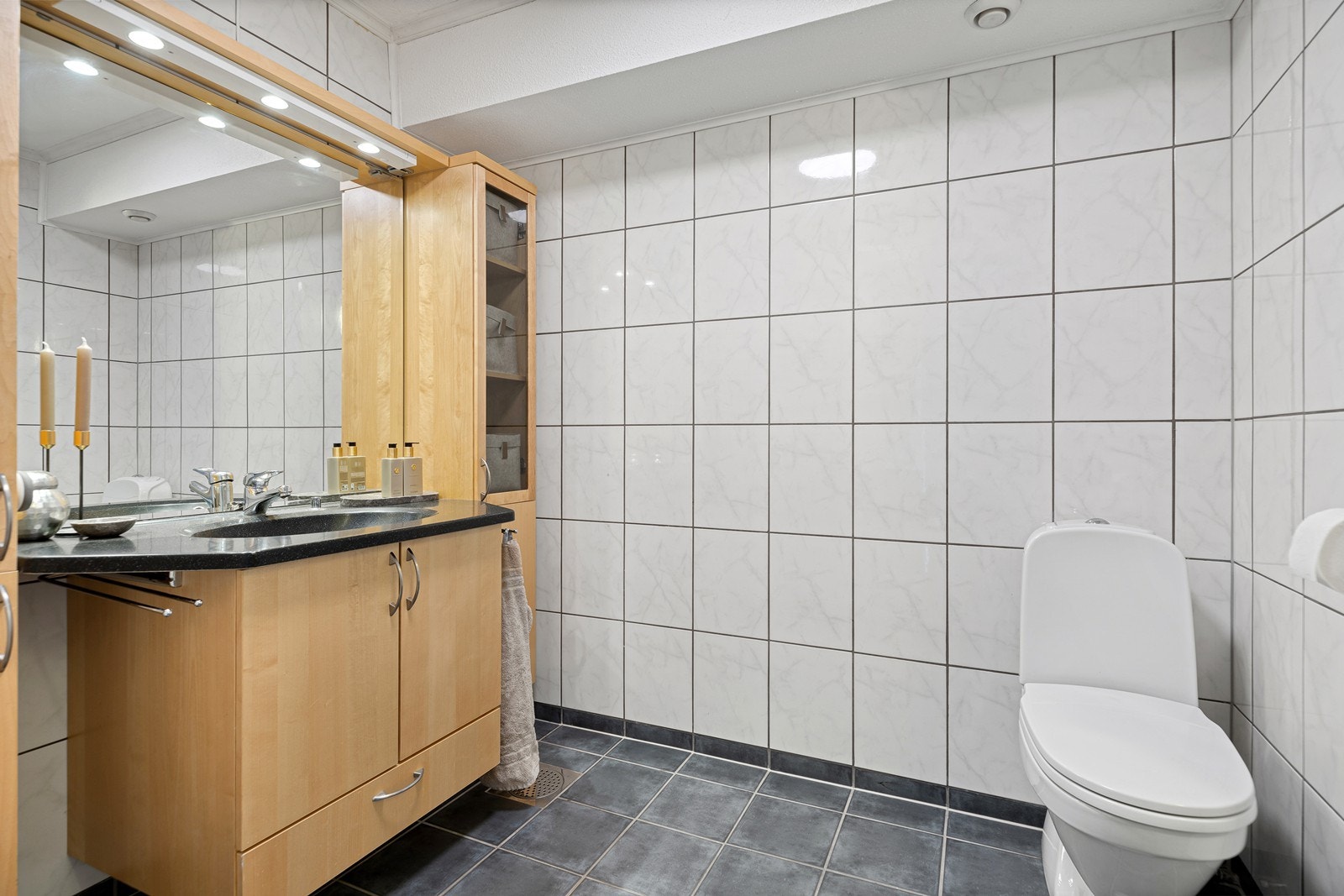 Badet er innredet med servantinnredning med speil og belysning, toalett og dusjsone Galleribilde