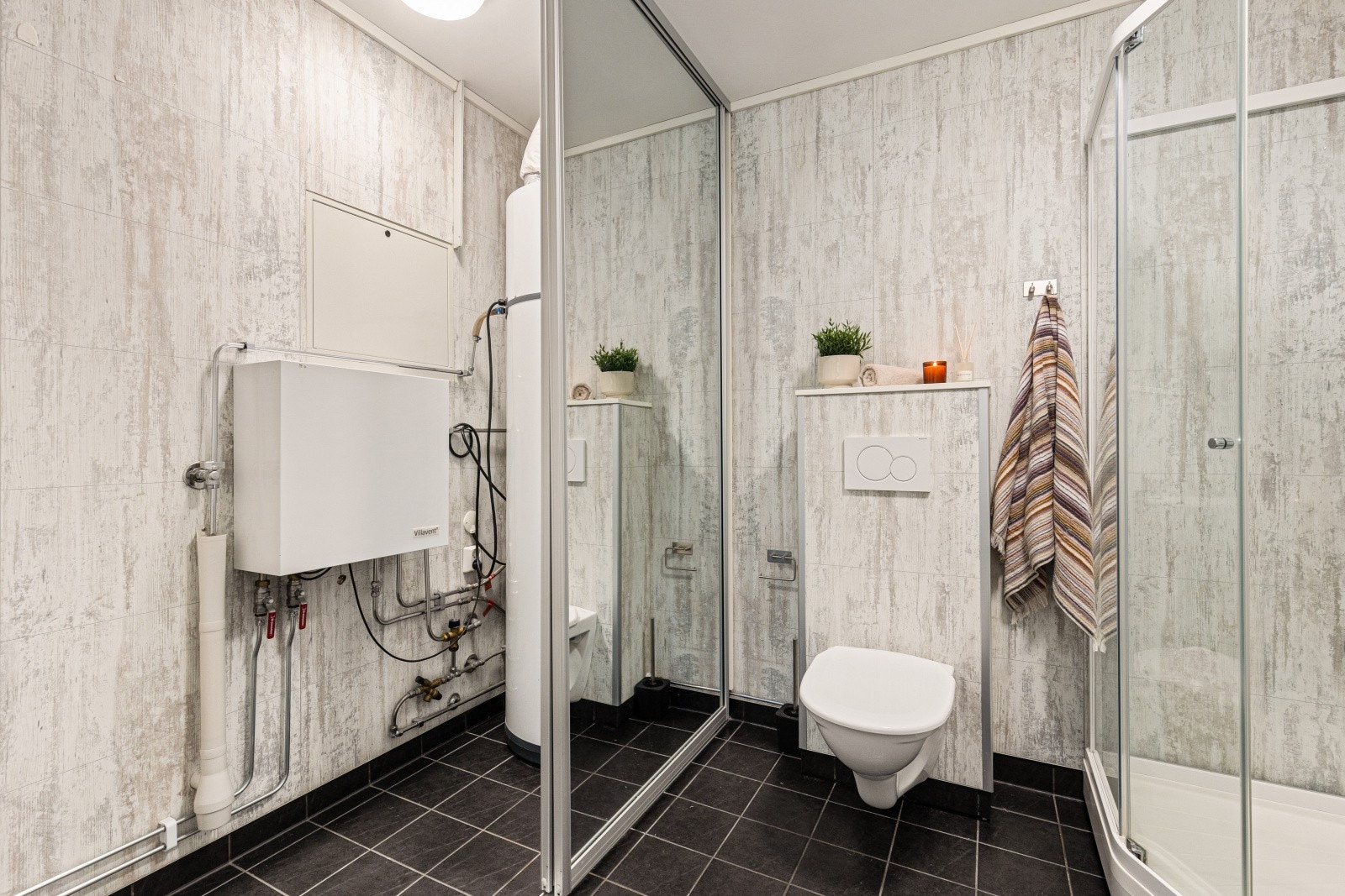 Badet har opplegg for vaskemaskin bak en praktisk skyvedørsgarderobe Galleribilde