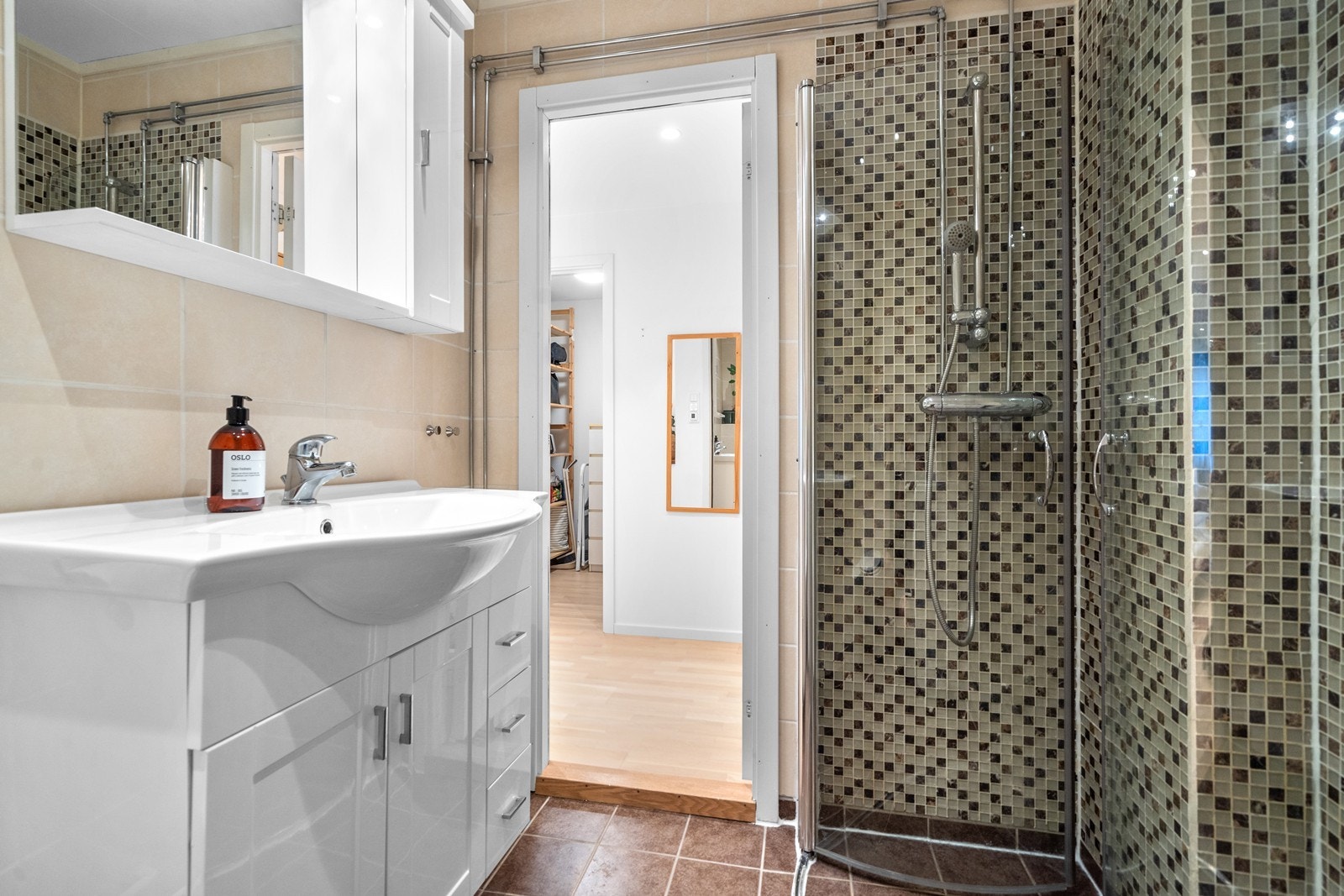 Badet er utstyrt med dusjhjørne med innfellbare glassvegger, vegghengt wc og servantinnredning med under- og overskap. Galleribilde