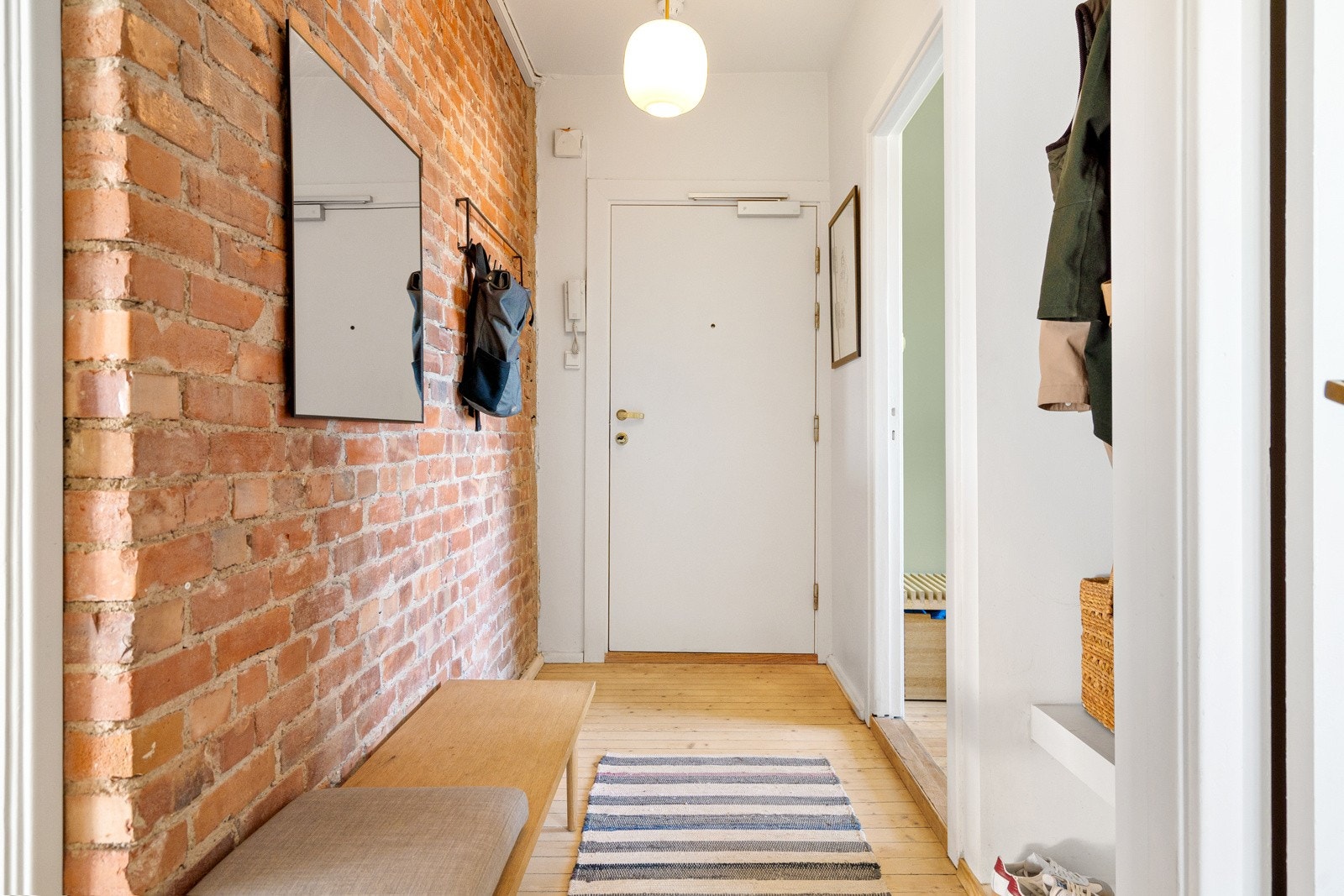 Pent gulv, tøff teglsteinsvegg og lyse farger på overflater gir et godt førsteinntrykk av boligen. Velkommen! Galleribilde