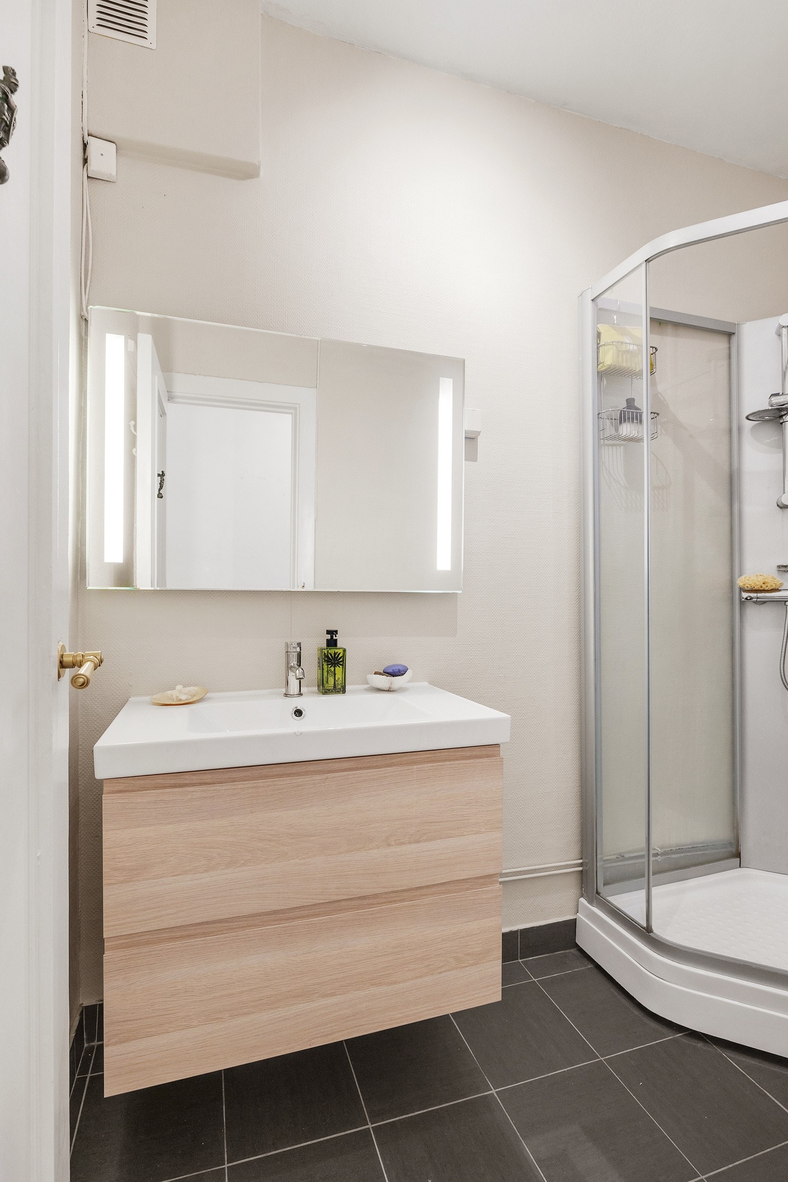 Badet inneholder vegghengt innredning med skuffer, speil med belysning, vegghengt wc og dusjkabinett. Galleribilde