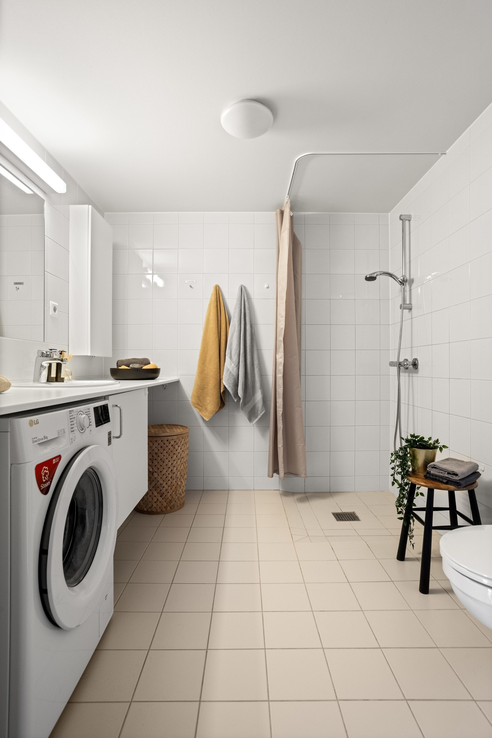 Badet har varmekabler, opplegg for vaskemaskin, vegghengt toalett og et åpent dusjhjørne Galleribilde