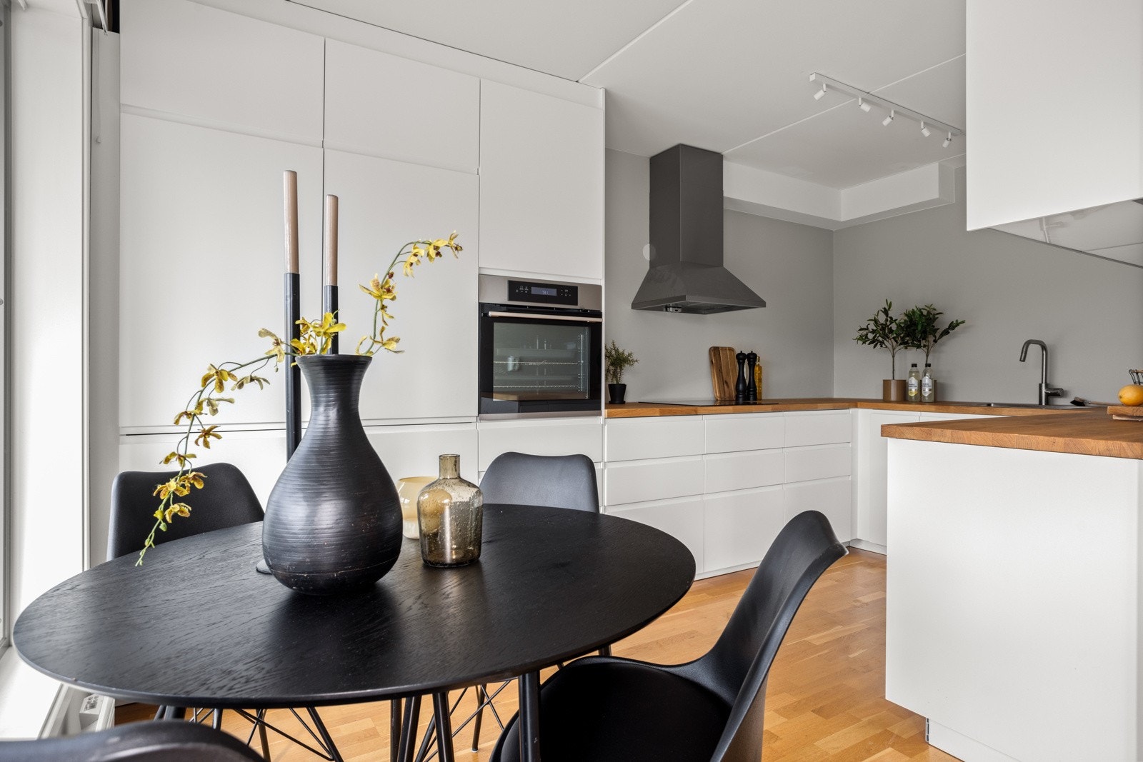 Kjøkkeninnredningen er stilren og moderne med integrerte hvitevarer, bestående av platetopp, stekeovn i høyskap, oppvaskmaskin og en kombinert kjøl/frys Galleribilde