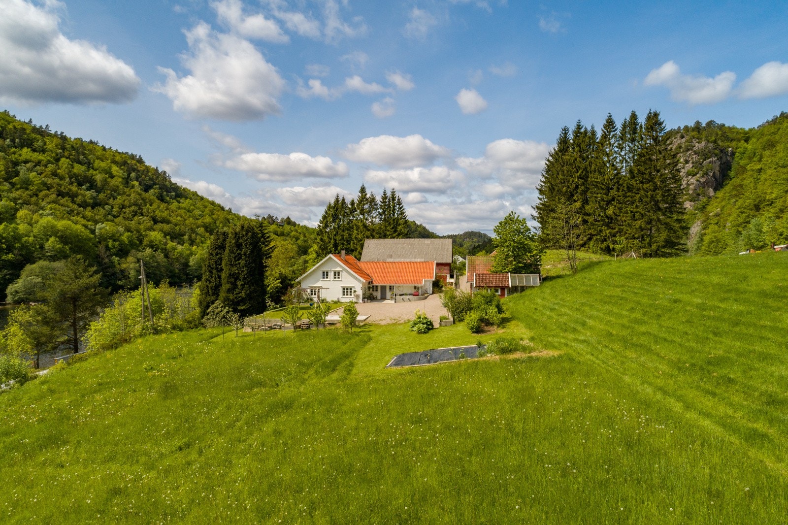 Gårdstunet er omringet av grønne marker og flott natur. Galleribilde