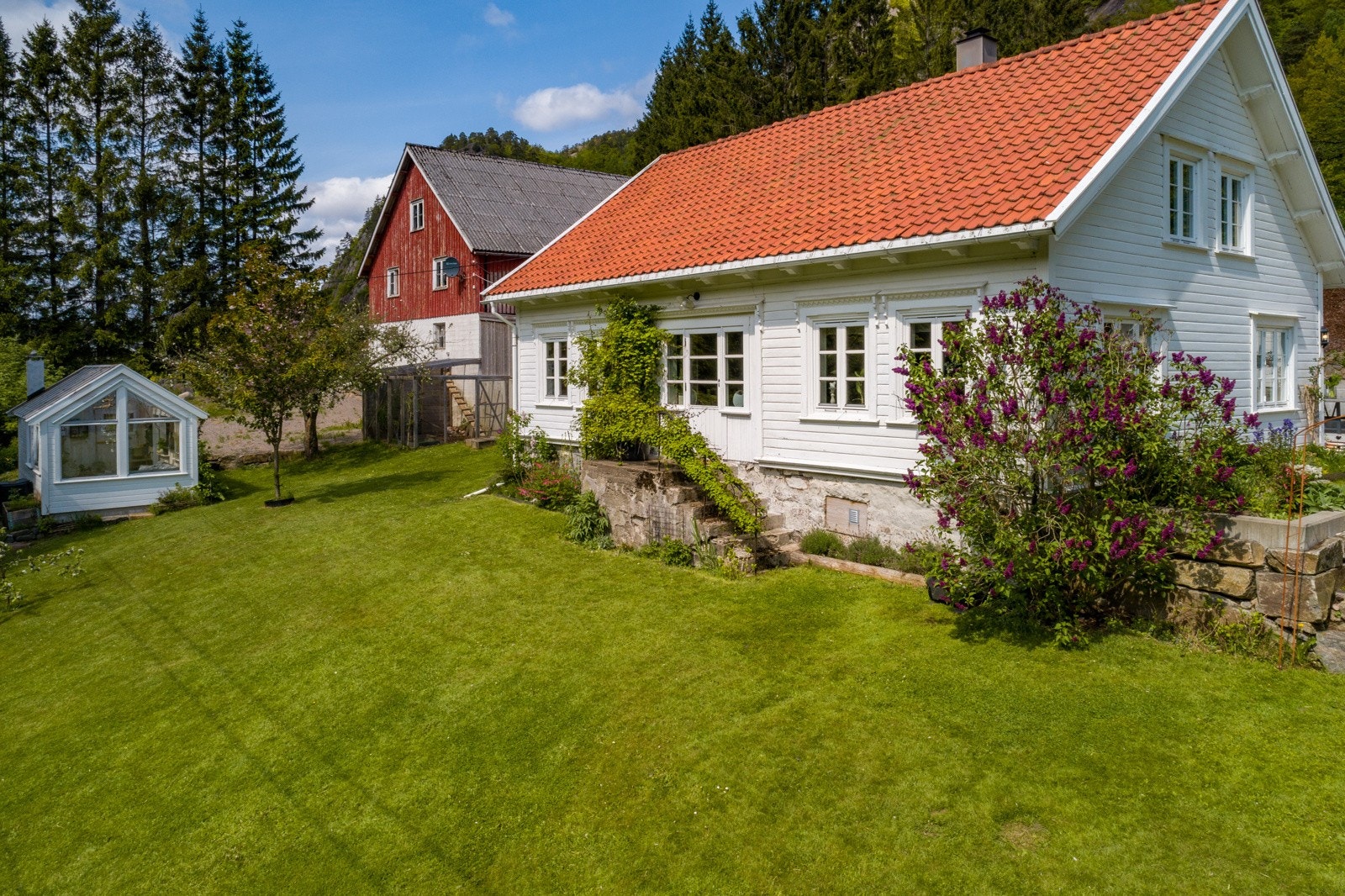 På boligens sydvestside er det fine blomsterbed og stort plenareal. Galleribilde