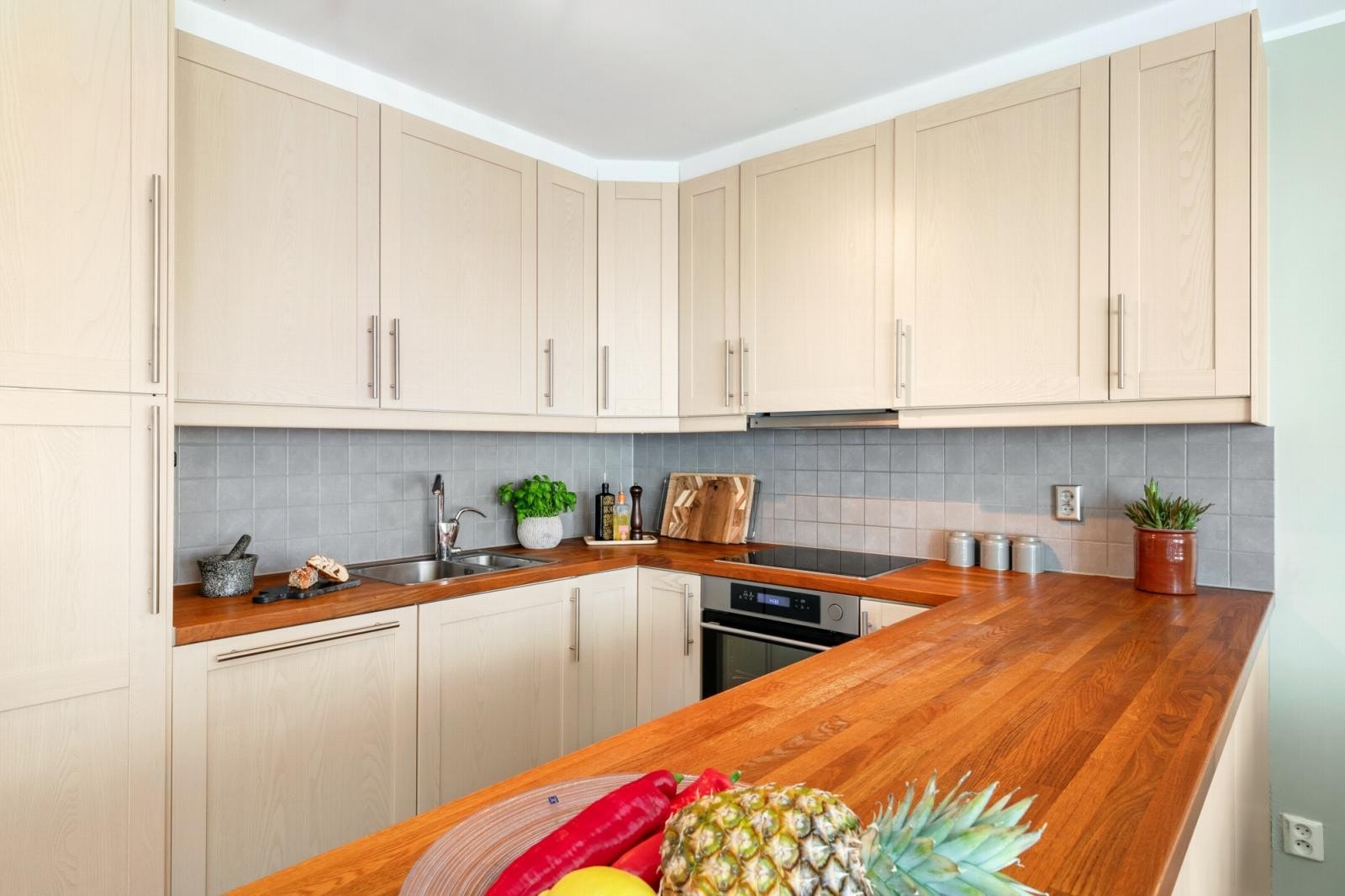 Godt vedlikeholdt kjøkken med benkeplater av tre og nedfelt oppvaskkum. Galleribilde