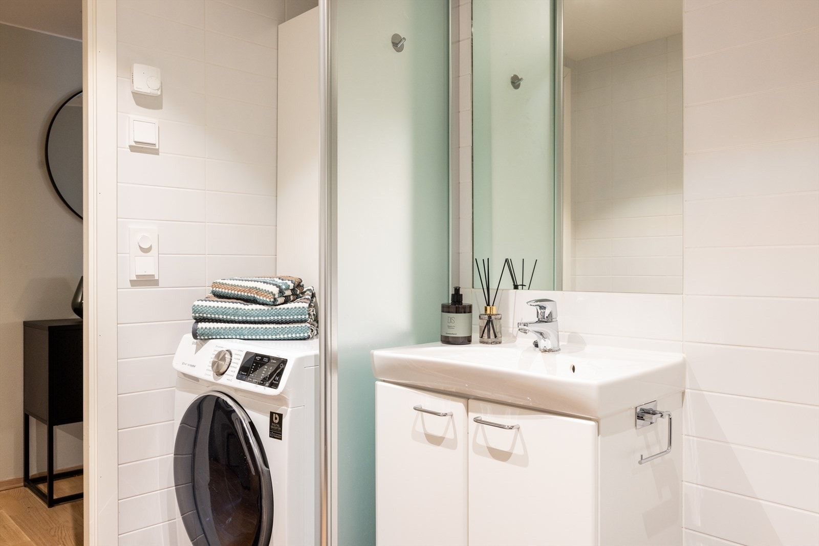 Badet består av vegghengt klosett, servant med innredning og dusjhjørne med svingbare glassdører. Det er opplegg for vaskemaskin. Galleribilde