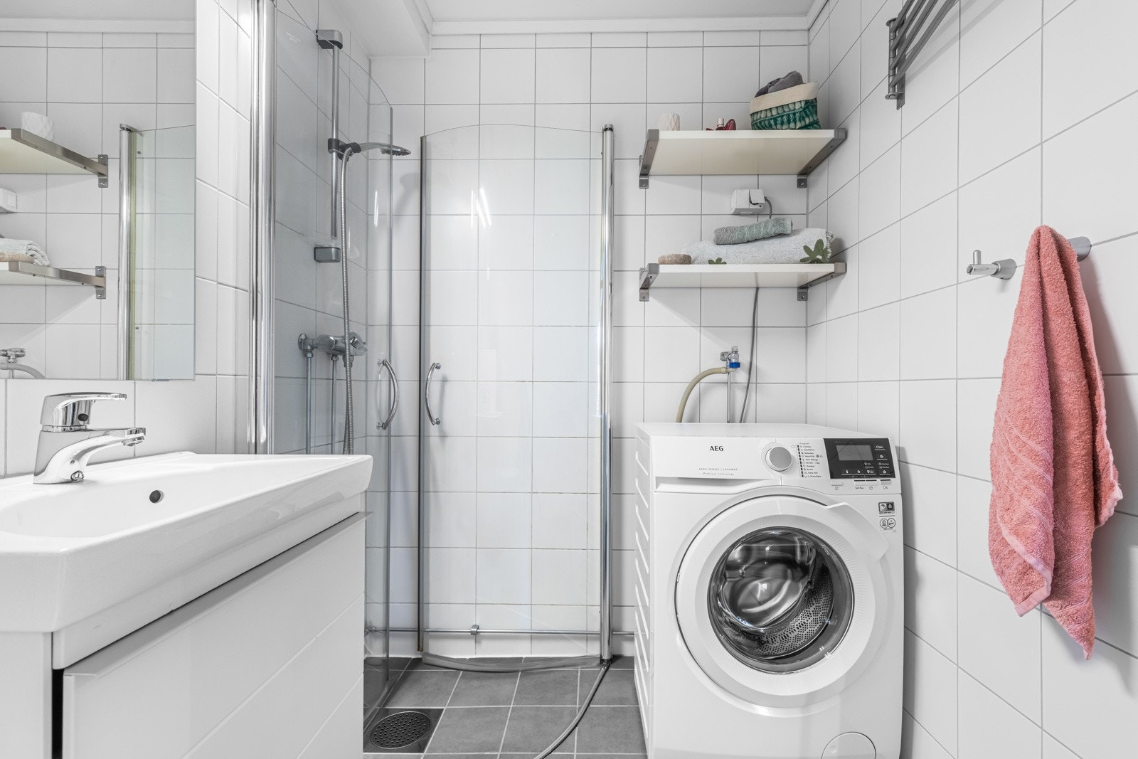 Videre har badet et vegghengt toalett, opplegg for vaskemaskin og et dusjhjørne med innfellbare glassdører. Galleribilde