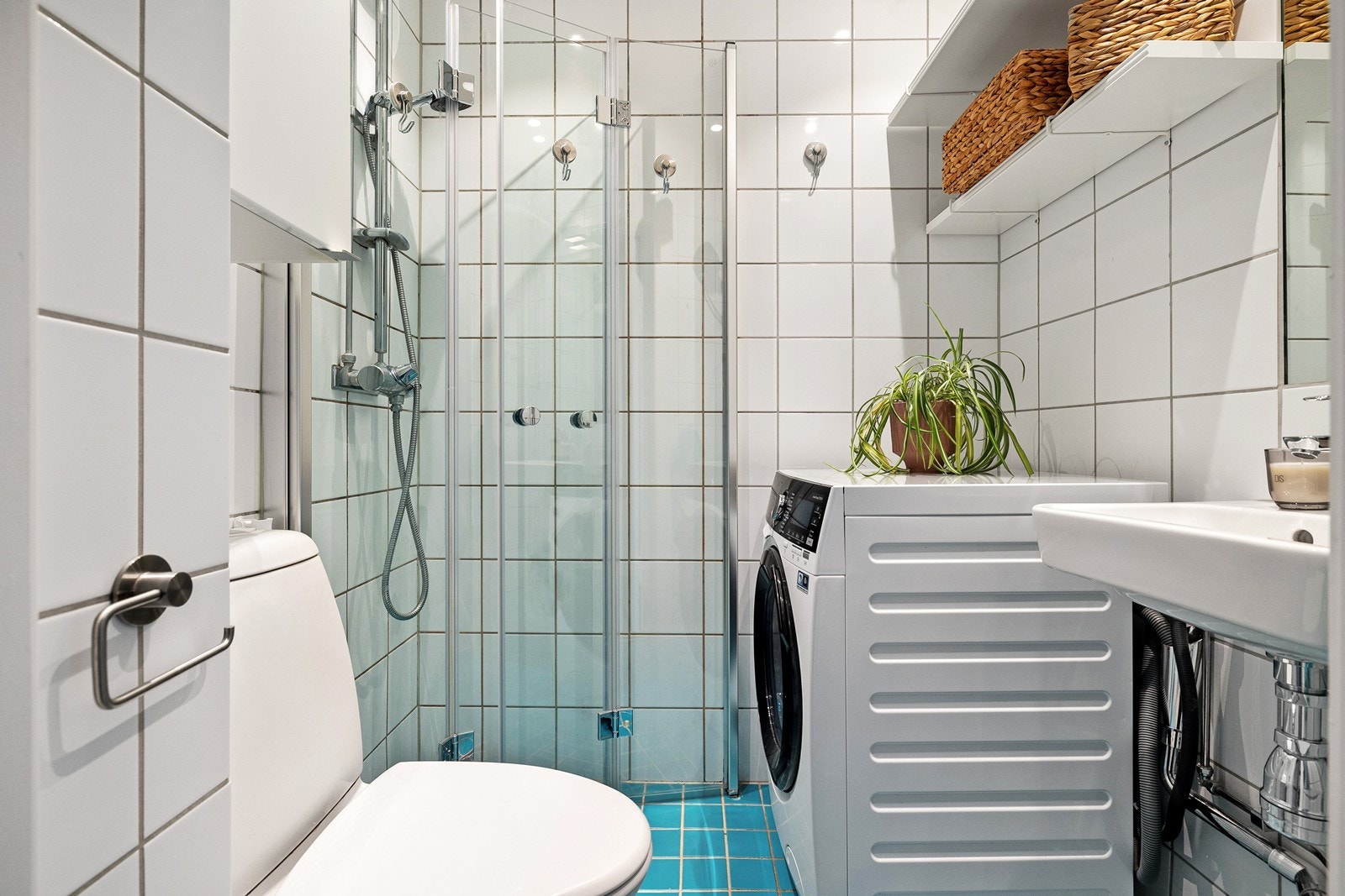 Lyst flislagt bad utstyrt med downlights, opplegg for vaskemaskin, servant, wc, dusjhjørne med innfellbare dusjdører og stoppekran. Galleribilde