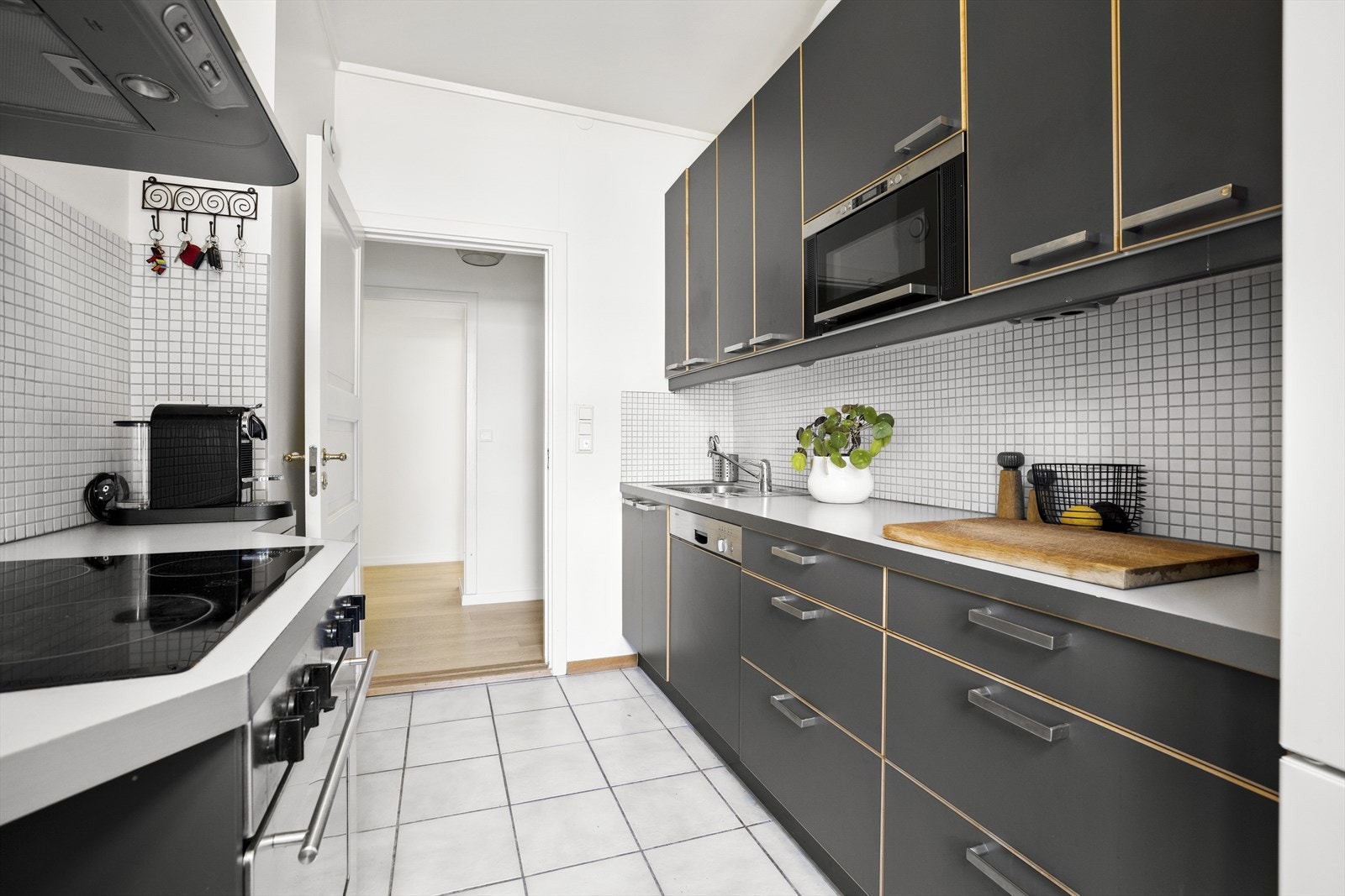 Delikat kjøkken i mørkere detaljer med lyse flislagte overflater, laminert benkeplate og gode oppbevaringsmuligheter. Galleribilde