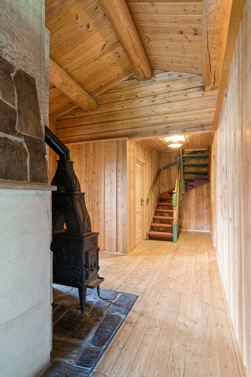 Man kommer inn i en romslig gang med god plass til å etablere gardeobeløsninger etter eget ønske. Her er det vedovn for oppvarming. Galleribilde