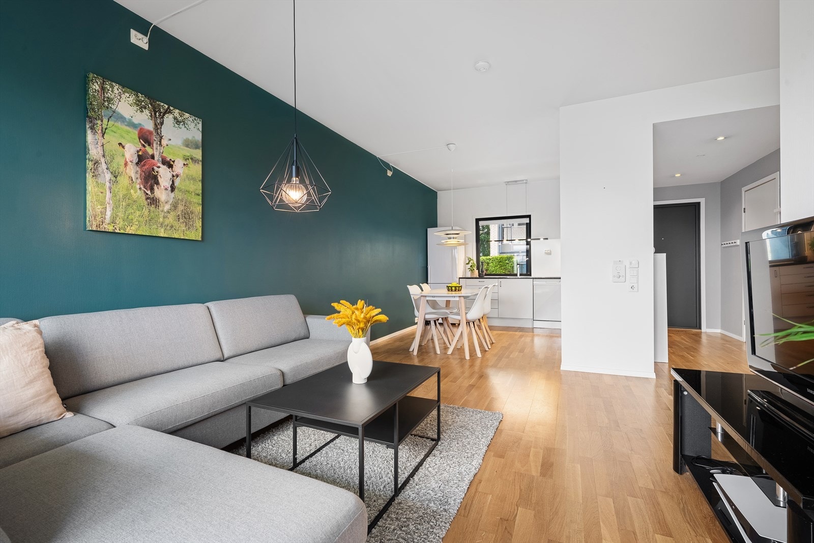 Stuens utforming gjør det enkelt å møblere hvor den store sofaen og tv'n får sin plass i motsatt ende av kjøkkenet, og spisebordet får sin naturlige plass i sonen mellom de to rommene. Galleribilde