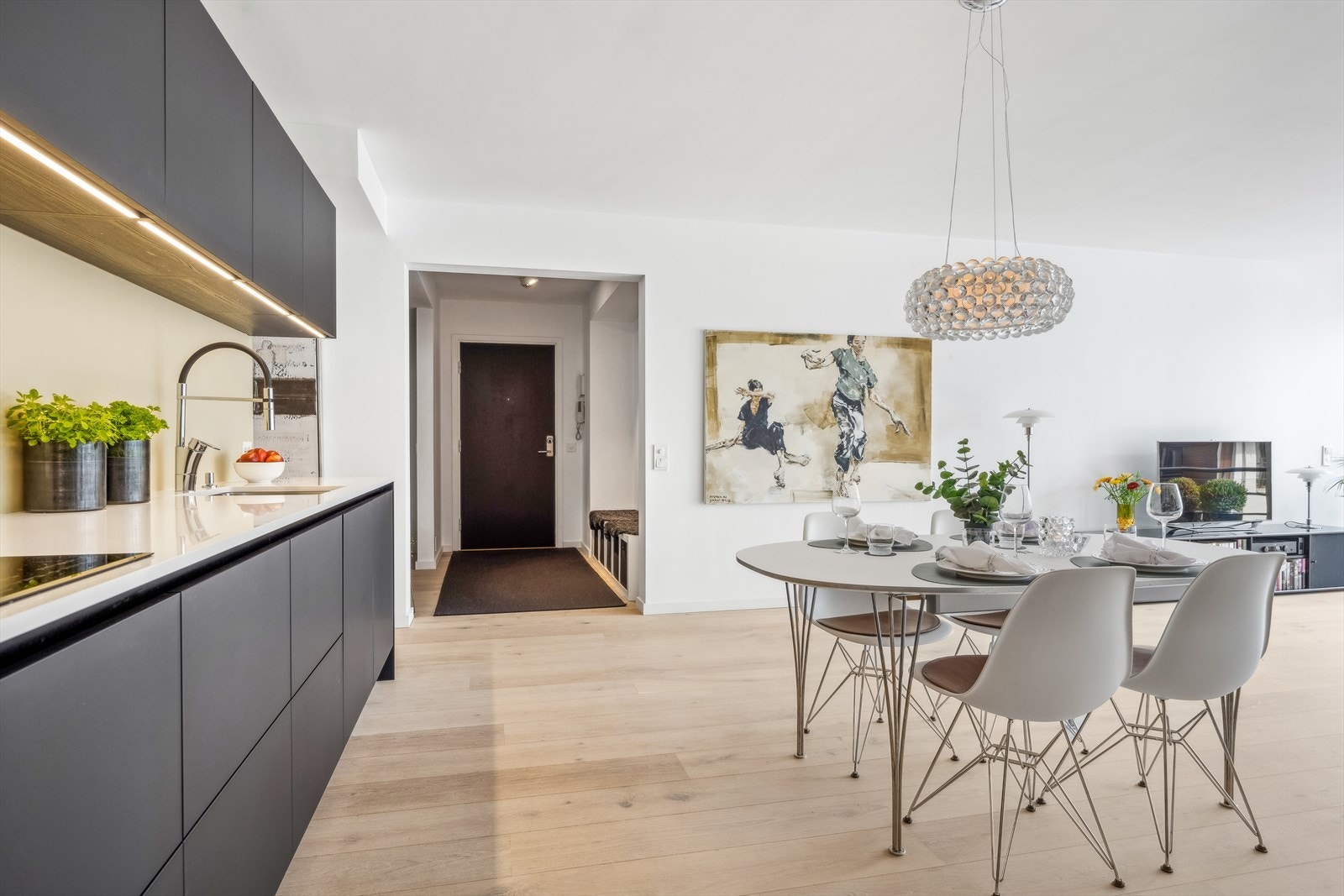 Pent og moderne kjøkken i åpen løsning med glatte fronter og komposittstein benkeplate med innfelt oppvaskkum og koketopp Galleribilde