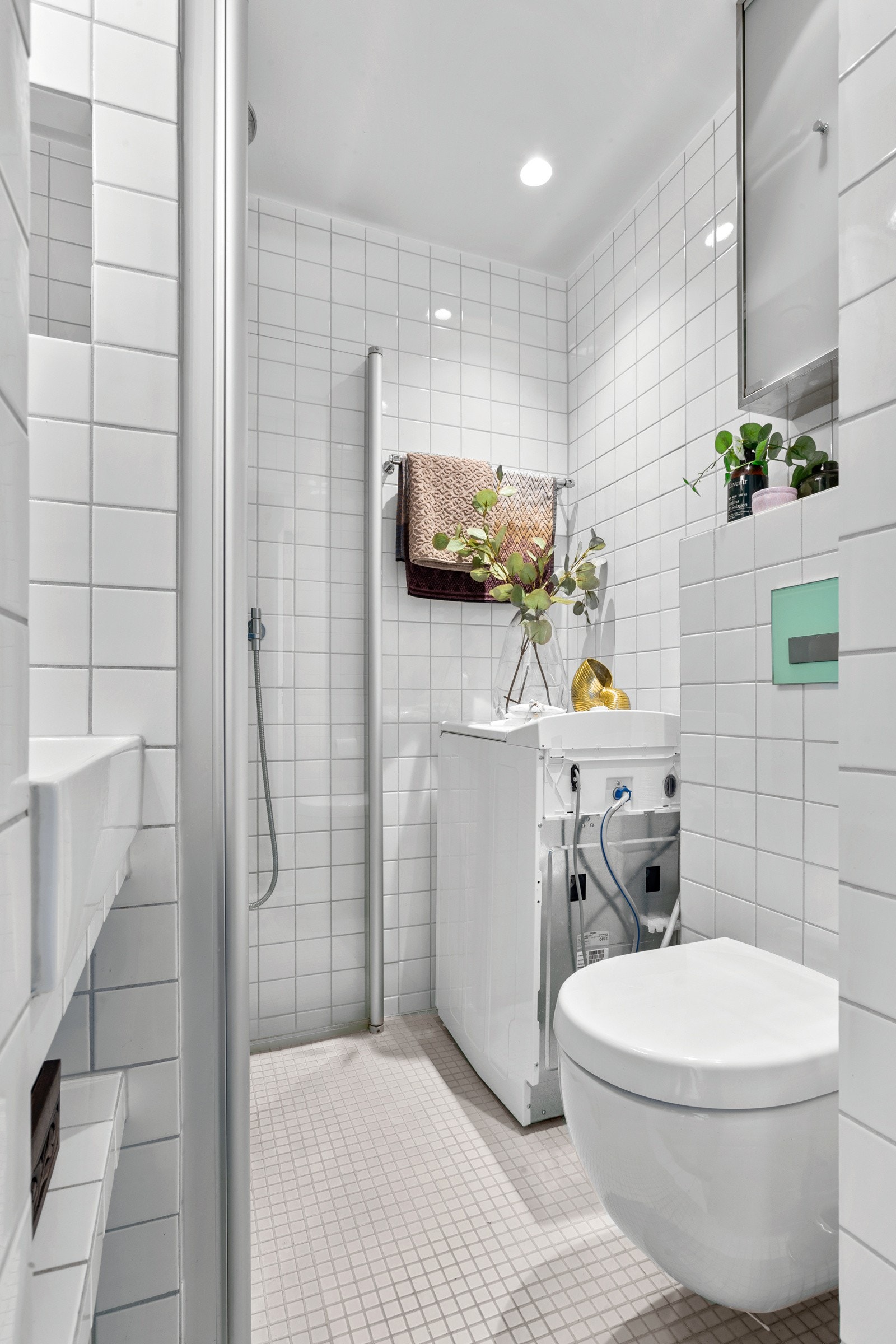 Badet har opplegg for vaskemaskin, varmekabler i gulv og downlights i tak Galleribilde