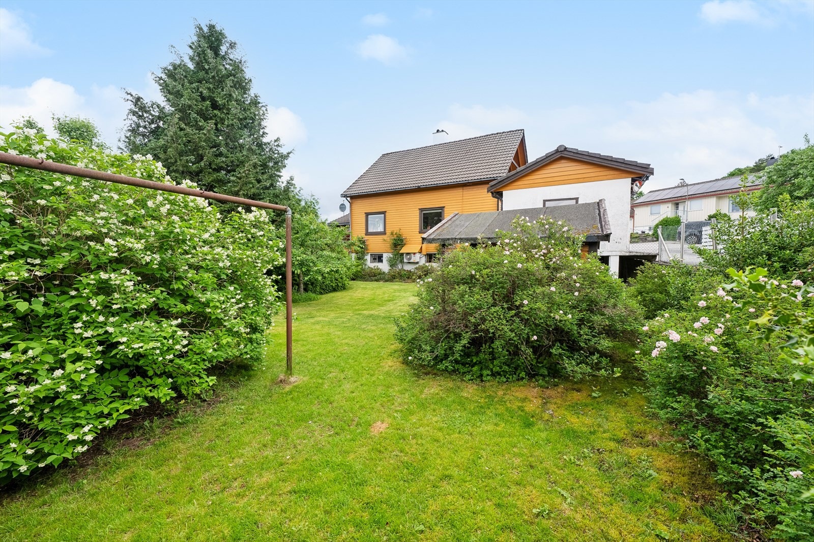Boligen ligger flott til på tomten. Usjenert hage innrammet av hekk og er beplantet med flotte vekster. Galleribilde