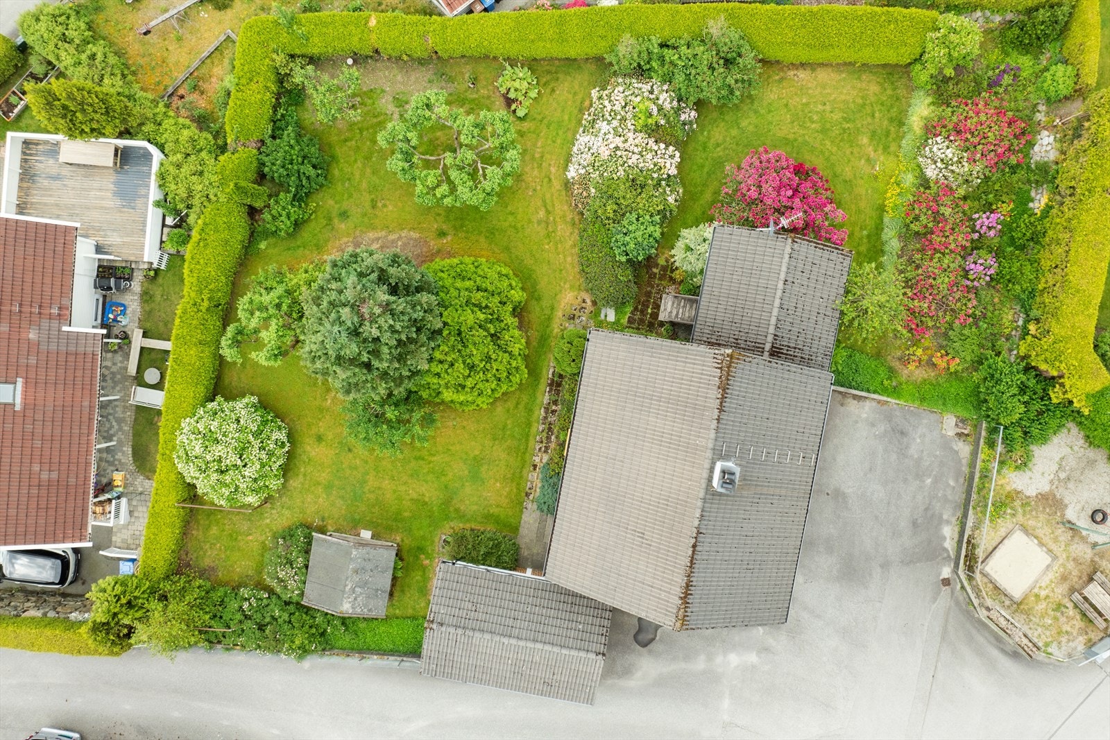 Boligen har et flott opparbeidet uteområde med bed, planter, busker og plen. Galleribilde