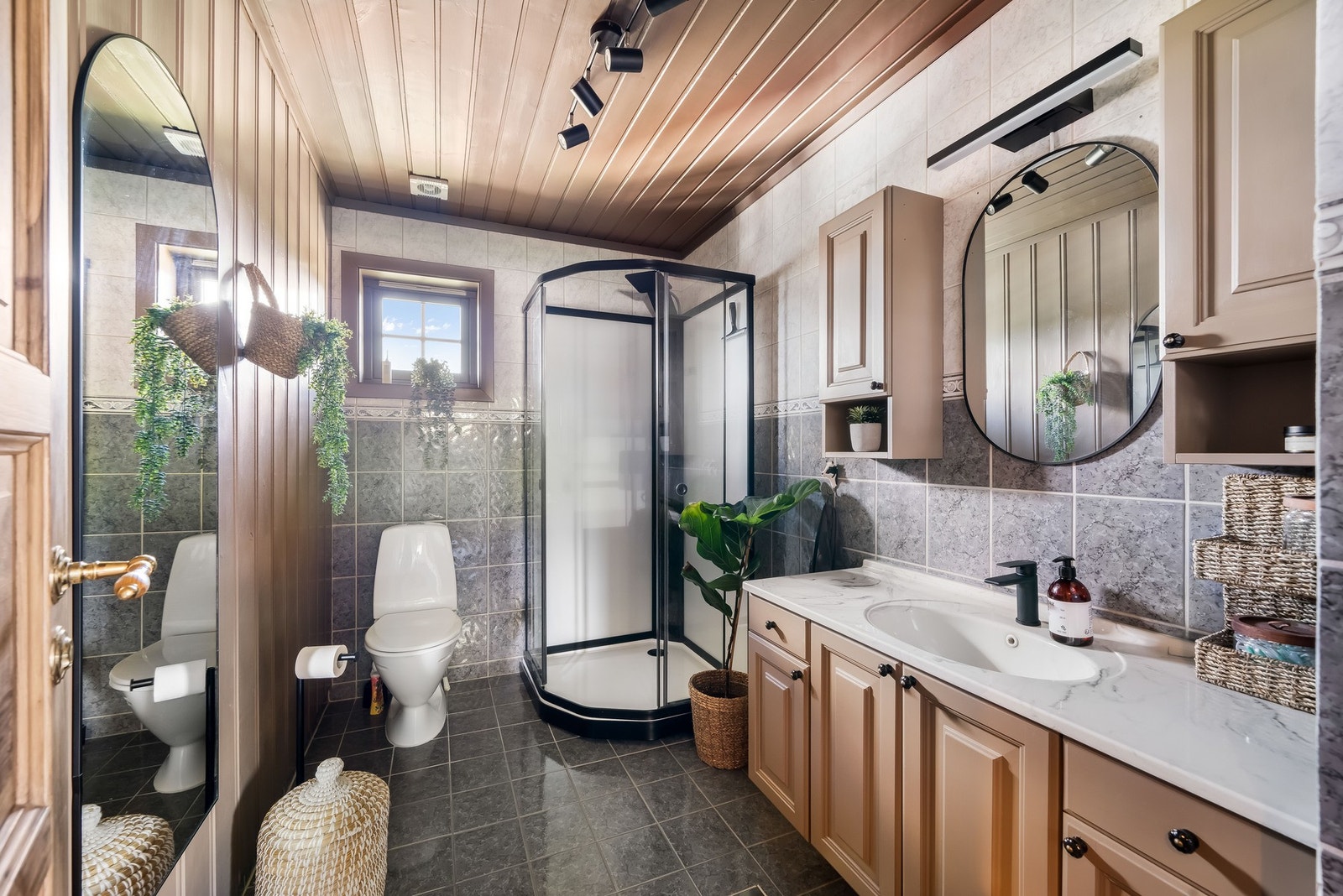 Bad fra omkring 1999. Gulv med flis og gulvvarme. Vegger med flis og malt trepanel. Himling med malt trepanel. Vegghengt servantinnredning med ett-greps blandebatteri, overskap og speil på vegg. Gulvstående toalett. Dusjkabinett satt inn i 2023 med to-gre Galleribilde