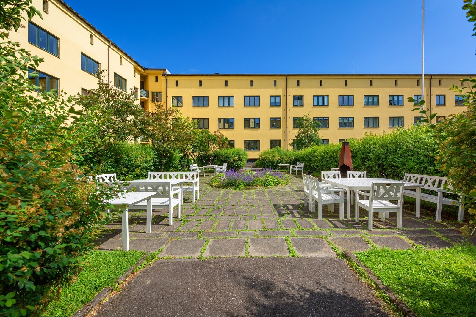 Stor og hyggelig bakgård med flere sittegrupper, utepeis og grill til bruk for beboerne Galleribilde