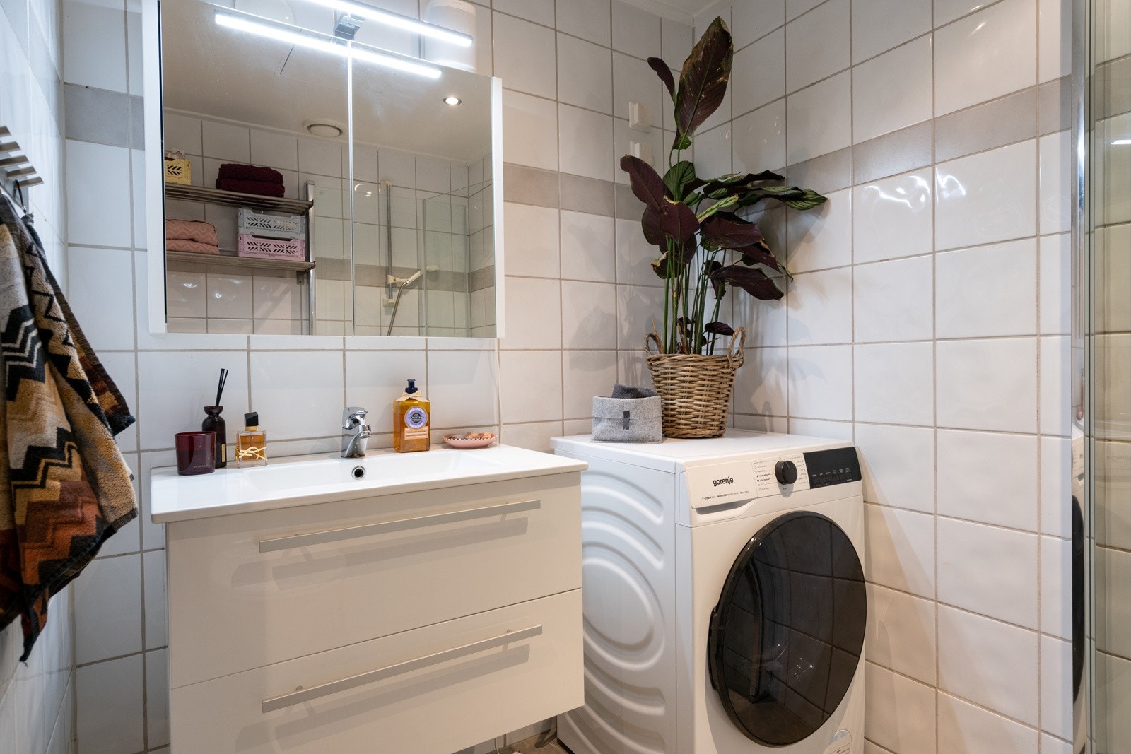 Baderomsinnredning med heldekkende porselenvask, gulvmontert toalett, dusjnisje med innfellbare glassdører fra 2024, vaskemaskin (også plass til tørketrommel) og baderomsinnredning på gulv samt vegg. Galleribilde