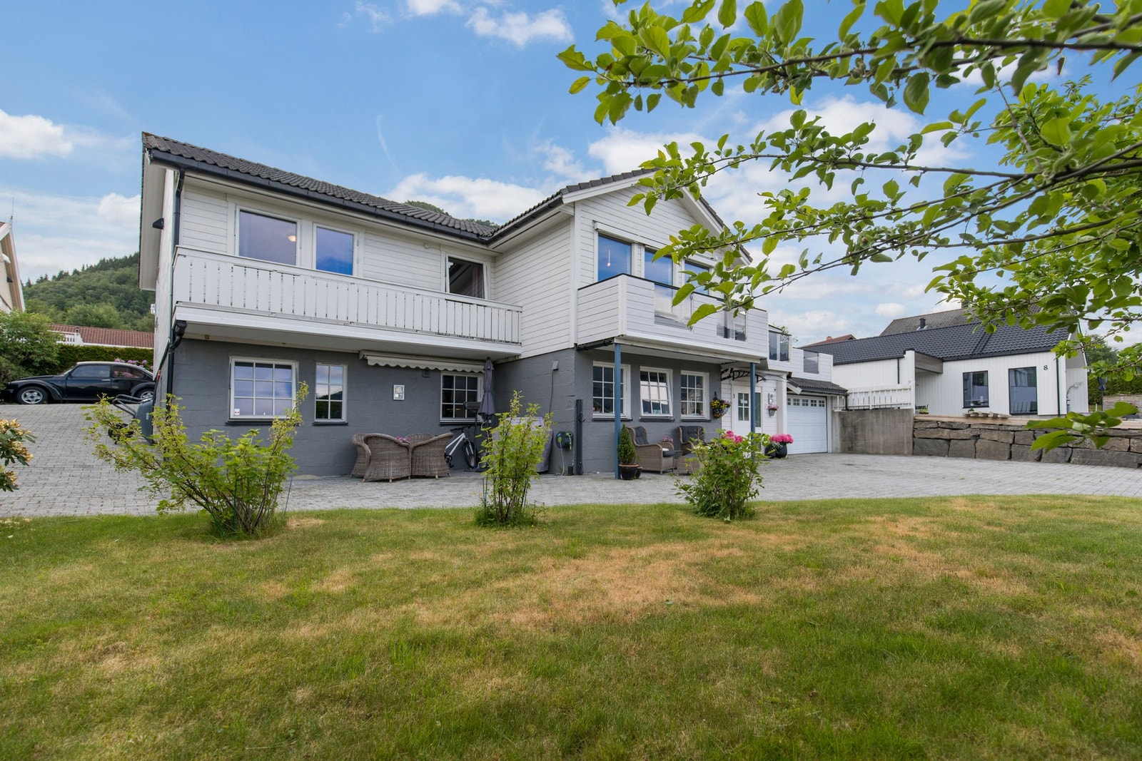 Tomten er opparbeidet med belegningsstein i innkjørsel, natursteinsmurer og grøntareal med plen og diverse beplantning. Galleribilde