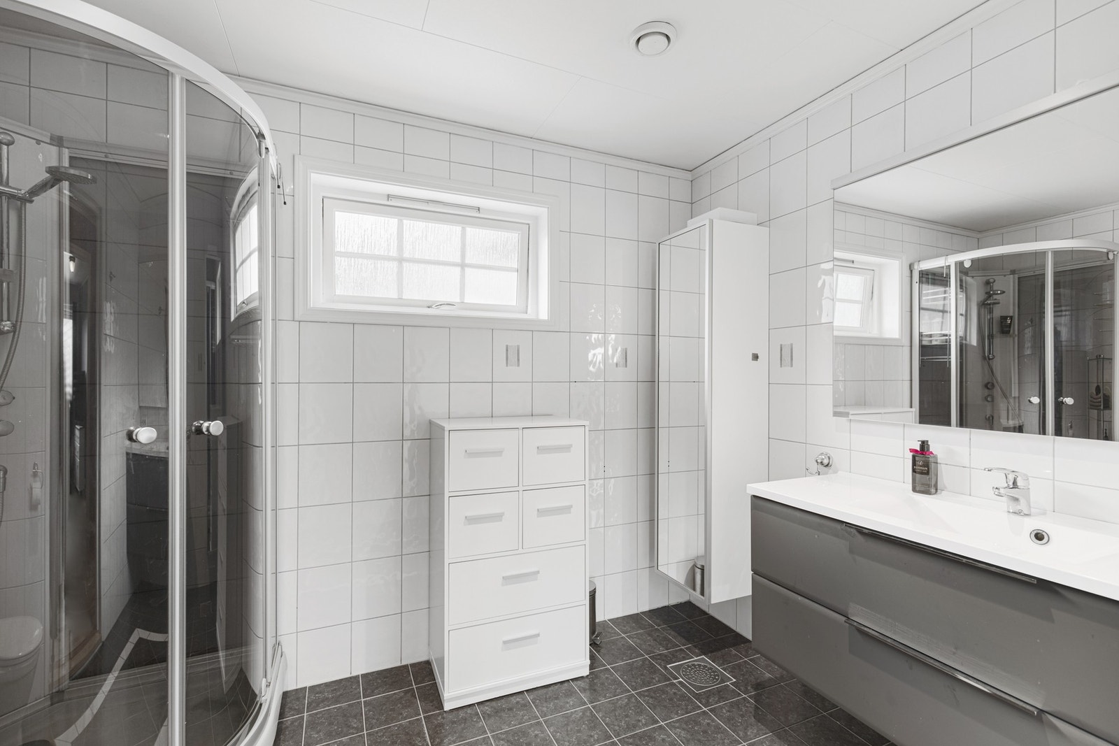 Etasjens bad er fra byggeår og har flis på gulv og vegger. Galleribilde