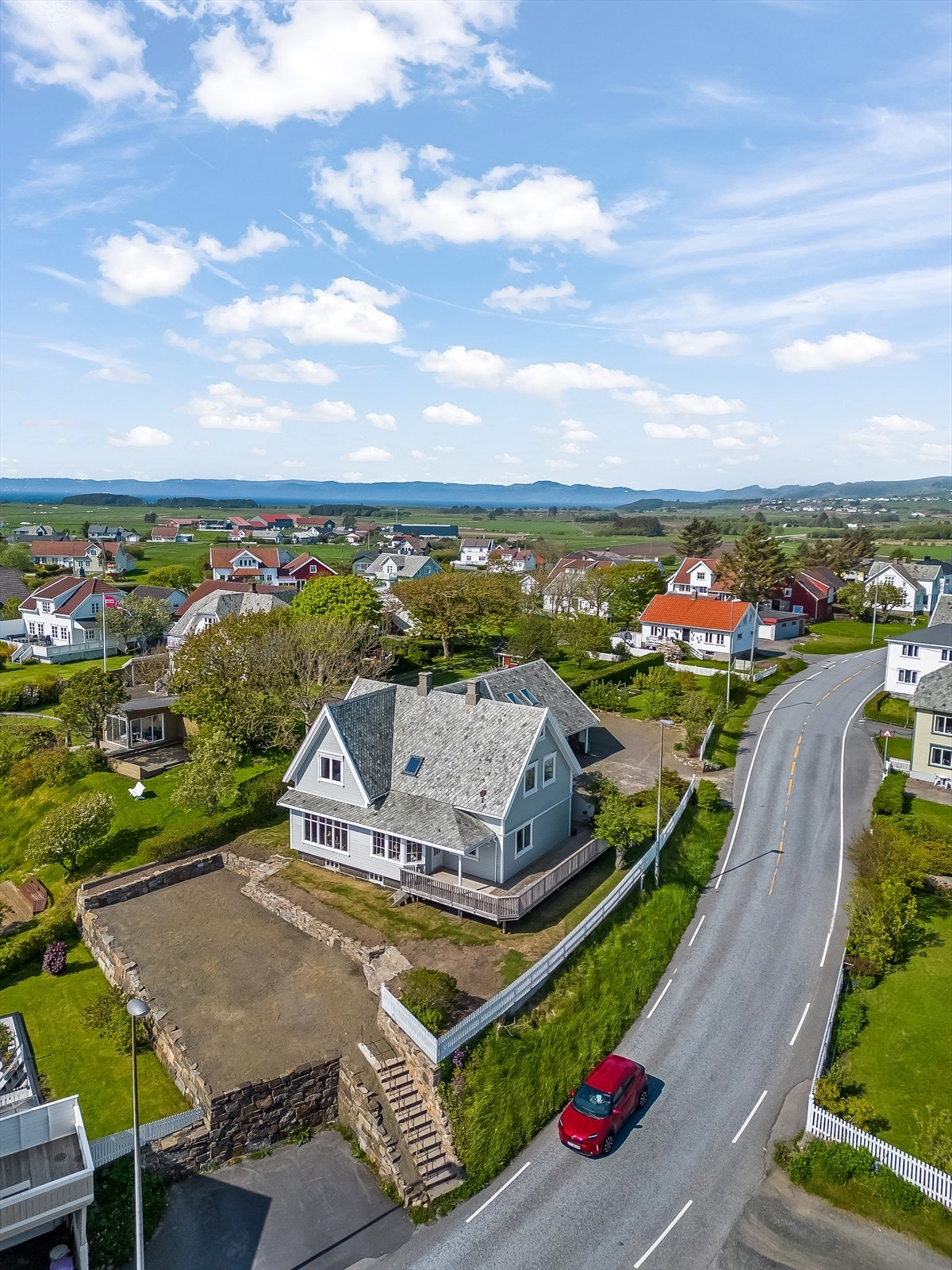 Planert område i front av boligen med flott steinsatt mur og trapp ned til veien. Galleribilde