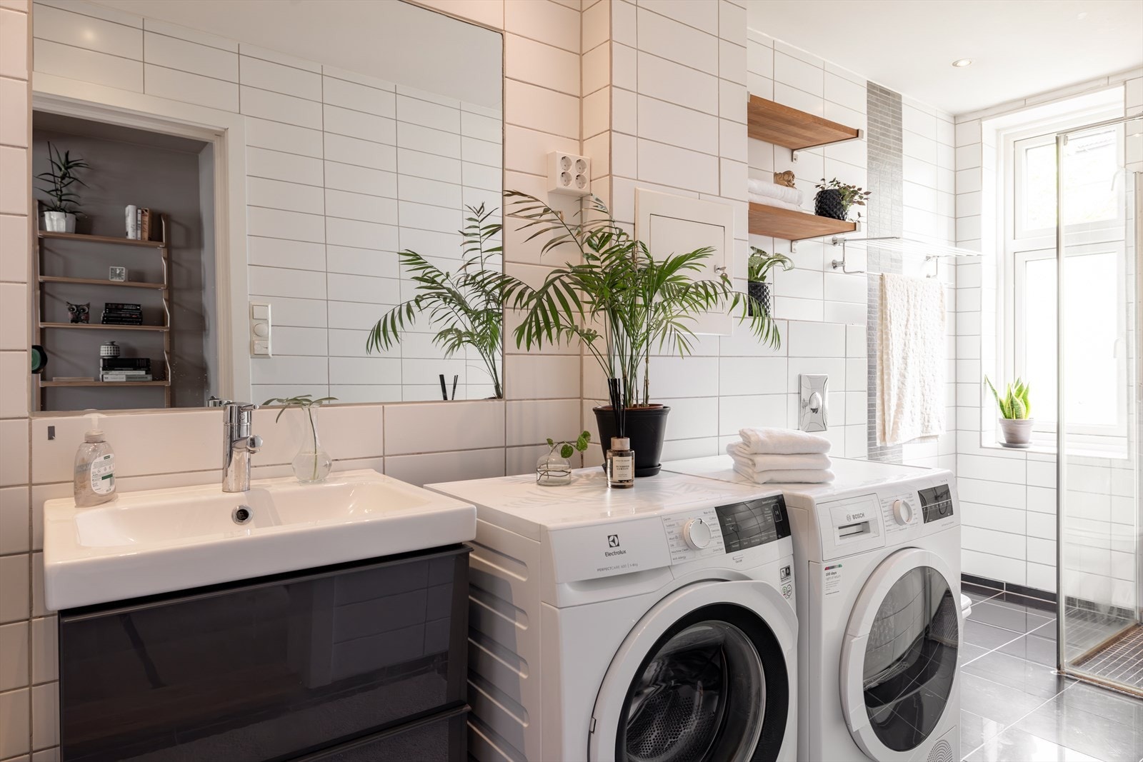 Det lyse, flislagte badet er innredet med dusj, vask og opplegg for vaskemaskin og tørketrommel. Galleribilde