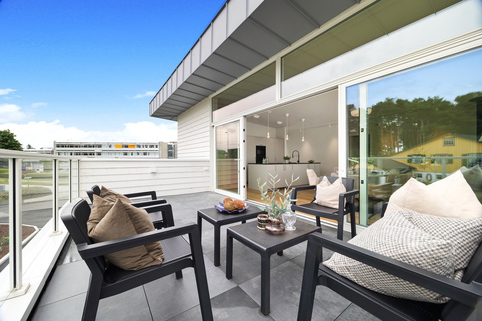 Terrassen har store fliser på gulvet og et luftig rekkverk av glass. Galleribilde