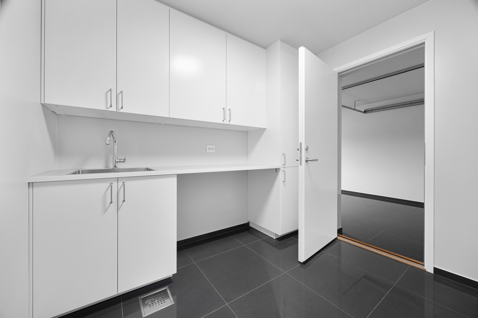 I den ene enden av rommet er det en takhøy, hvit innredning med slette fronter, kjekk arbeidsbenk og rustfritt kum. Galleribilde