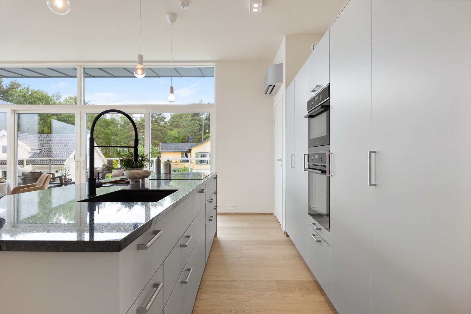 Kjøkkenøya har benkeskap på to sider, en sort benkeplate i stein, oppvaskkum og nedfelt koketopp med integrert ventilator. Galleribilde