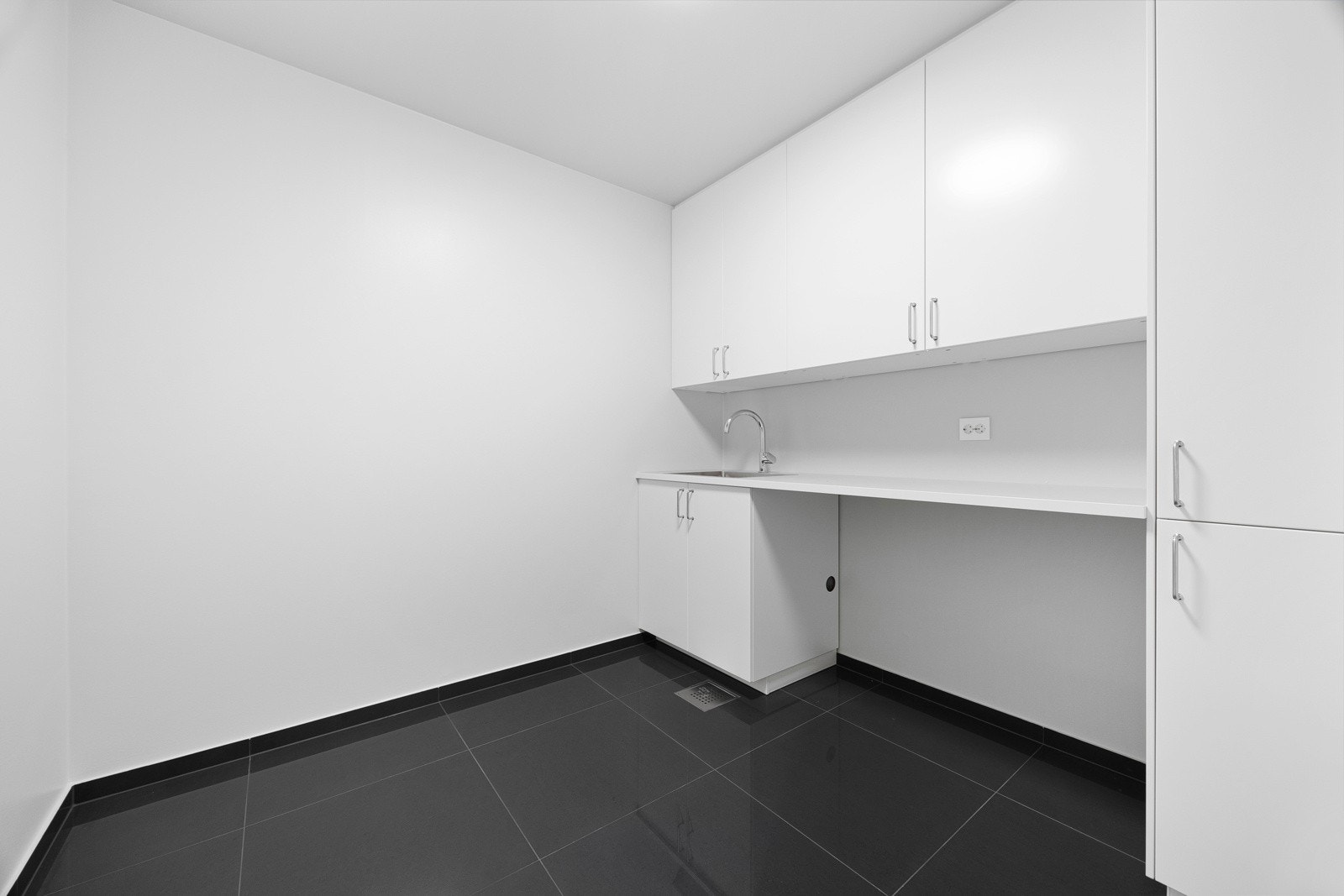 Vaskerommet ligger i første etasje og fungere som en sluse fra garasjen. Rommet har store, sorte gulvfliser med gulvvarme og like sokkelfliser med lysmalte vegger over. Galleribilde