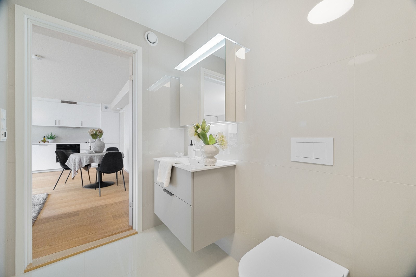 Baderommet har lik stil som i hoveddelen med sandfargede fliser på vegger og gulv, gulvvarme, vegghengt toalett og opplegg for vaskemaskin. Galleribilde