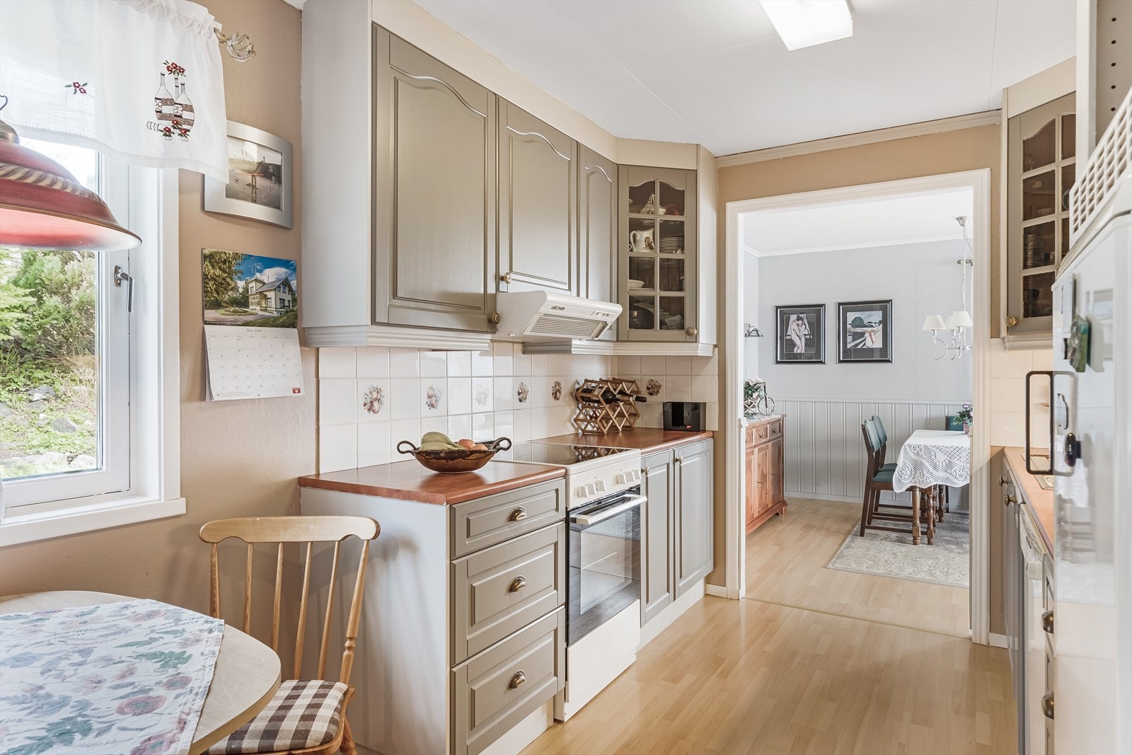 Kjøkkeninnredning fra Vevelstad Trevare i profilerte fronter med over- og underskap, laminert benkeplate og flis på vegg mellom benk og overskap. Galleribilde