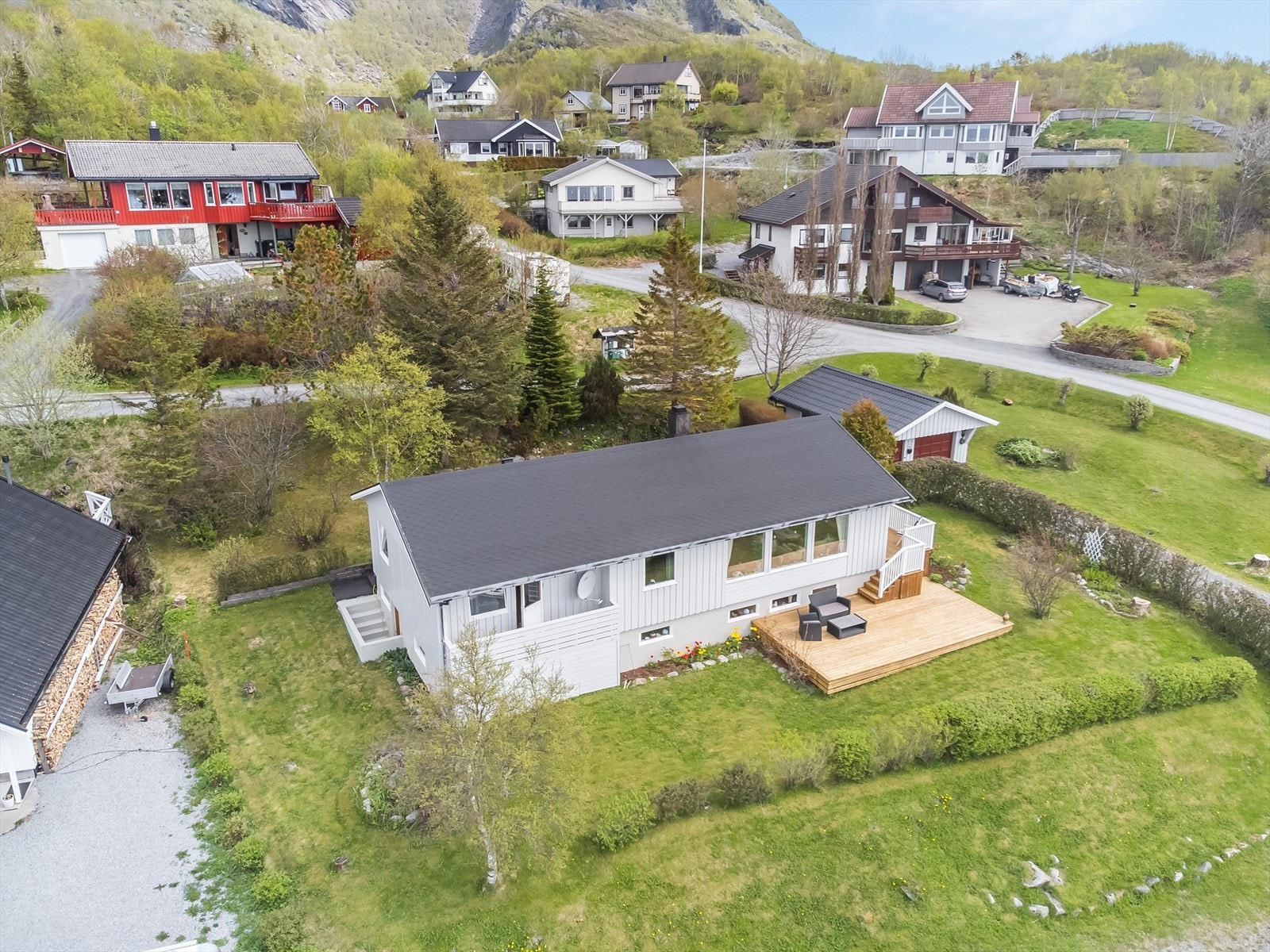 Pent opparbeidet tomt med plen, bedd, hekk, busker og trær. Galleribilde