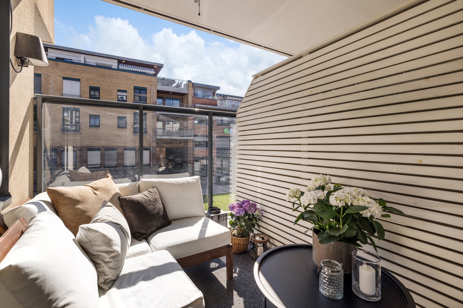 Østvendt balkong med takoverbygg og levegger. Rekkverk med glass i front. Galleribilde