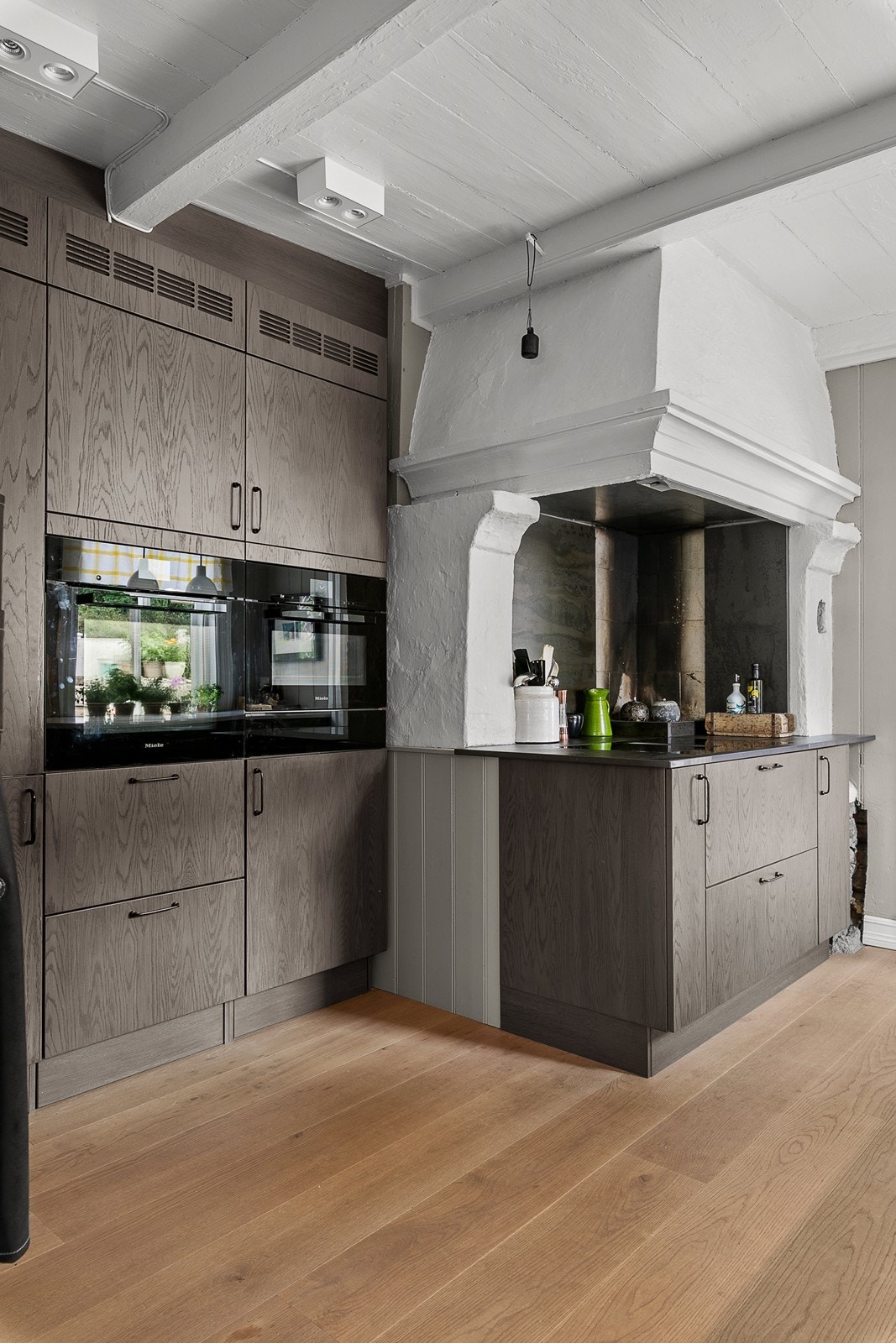 De stramme, rette kjøkkenfrontene med liggende eikefinér skaper et stilrent og lekkert kjøkken. Galleribilde