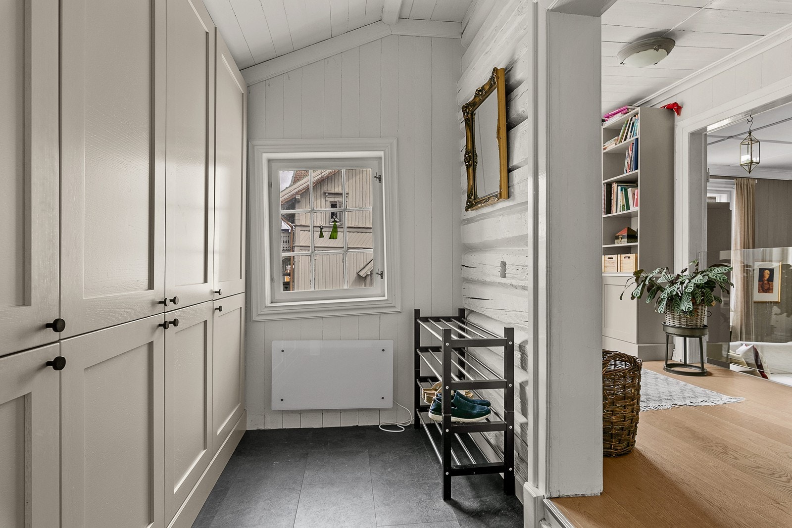 Vindfanget og gangen gir en forsmak på hva som venter videre inn i huset, med synlig tømmervegg og et glimt av husets atmosfære. Galleribilde