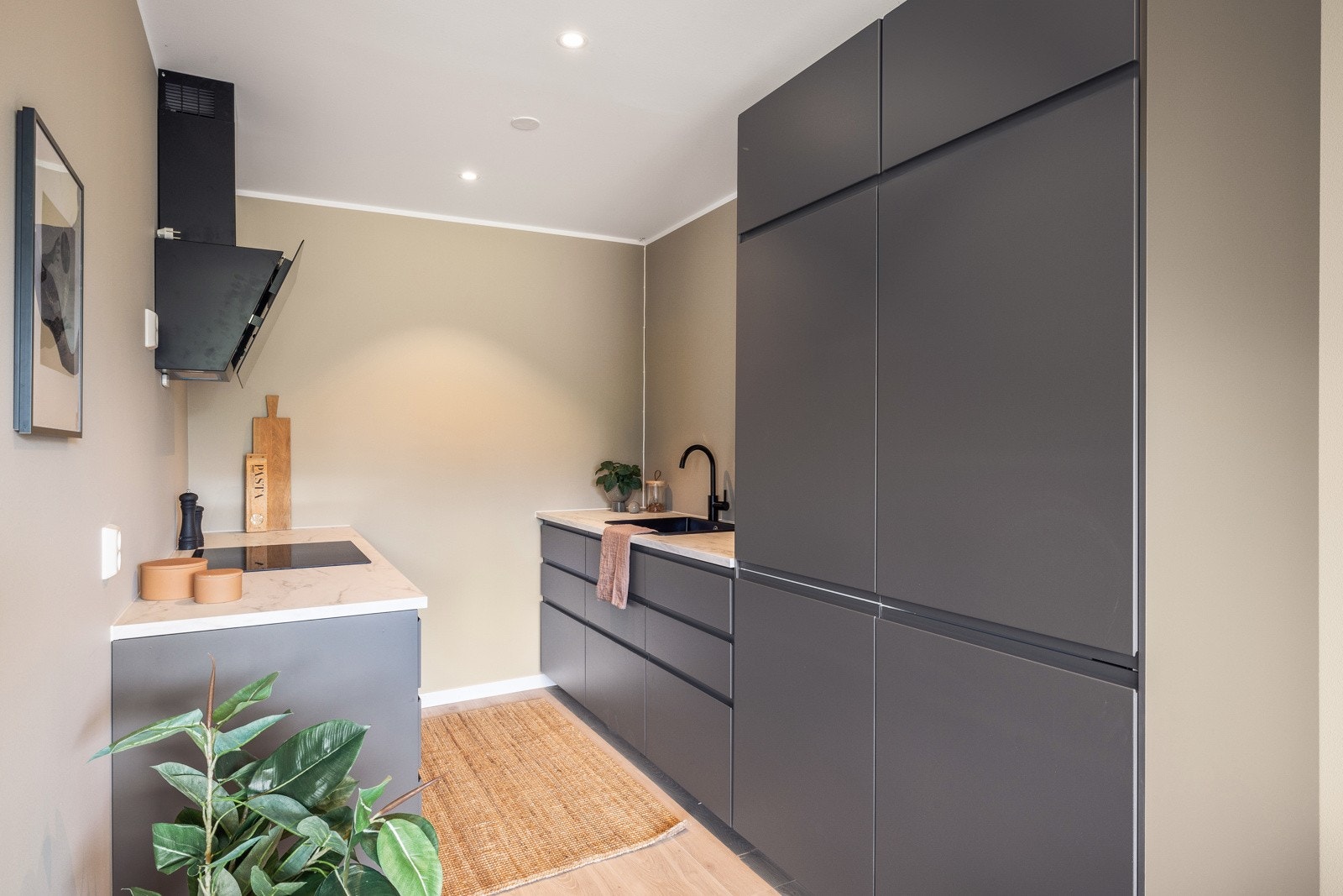 Kjøkkenet inneholder laminert benkeplate, kompositt vaskekum, ventilator og opplegg for oppvaskmaskin Galleribilde