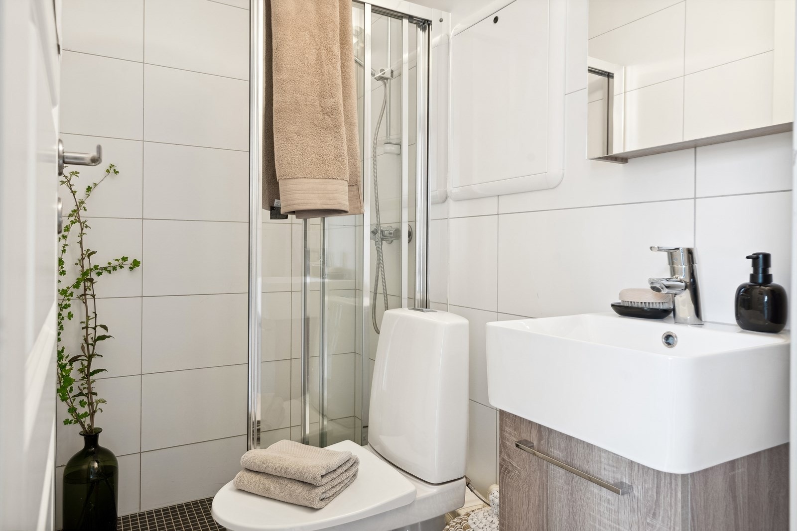 Pent og klassisk bad fra 2011 som inneholder toalett, dusj med vegg og ellers servant med skapinnredning Galleribilde