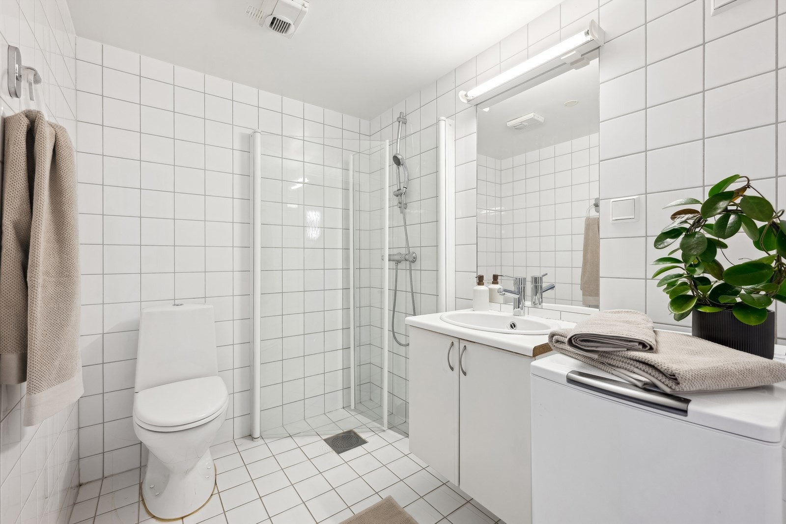 Pent, flislagt baderom fra 2006 med varmekabler i gulv. Badet er innredet med dusjnisje med innfellbare glassdører, servantinnredning og toalett. Opplegg for vaskemaskin og tørketrommel i søyle. Galleribilde