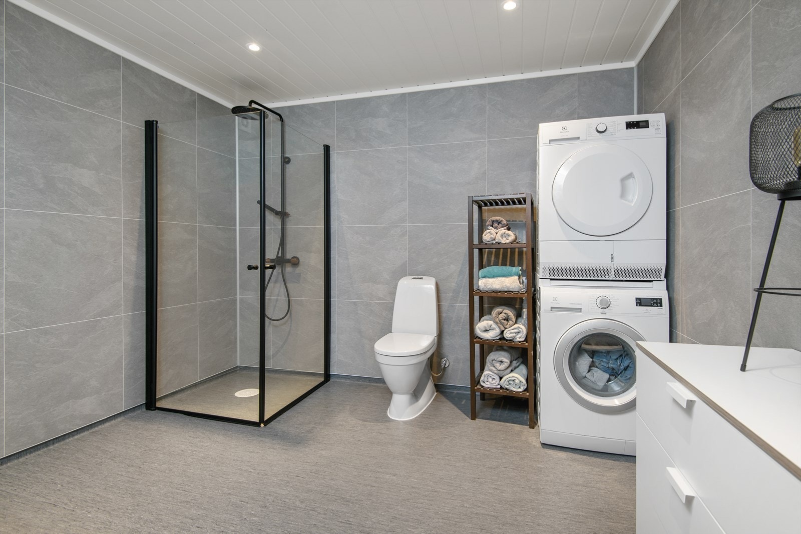 Stort bad med opplegg for vaskemaskin, tørketrommel, WC og dusjhjørne. Galleribilde