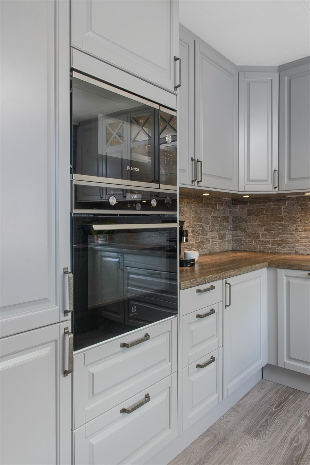 Kjøkken med profilerte fronter og integrert oppvaskmaskin, kjøleskap, komfyr og mikrobølgeovn. Galleribilde