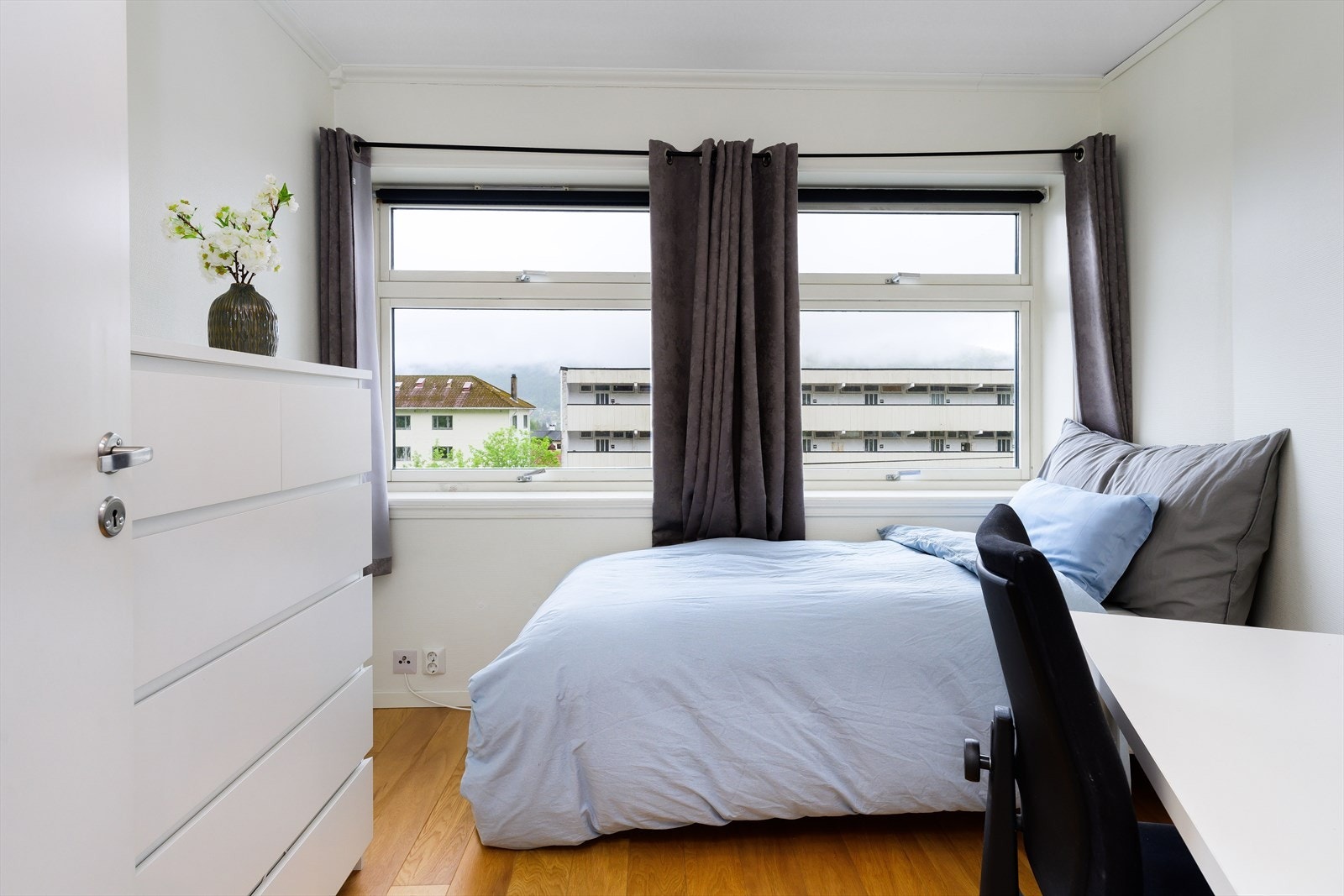 Lys og tiltalende rom brukt som soverom med store vinduer og moderne innredning, perfekt for ro og avslapning. Galleribilde