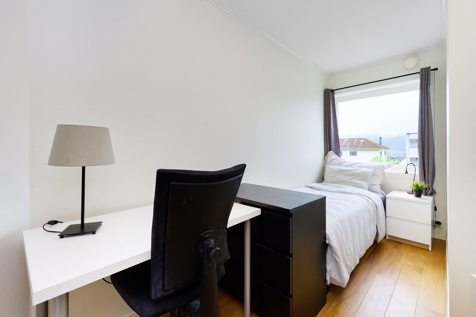 Lys og innbydende soverom med praktisk arbeidsplass og utsikt mot rolig nabolag. Soverom 2. Galleribilde