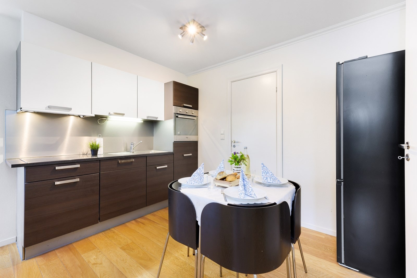 Moderne kjøkken med integrerte hvitevarer og stilren design. Praktisk spiseplass med plass til fire. Integrert kjøleskap under ovn. Galleribilde