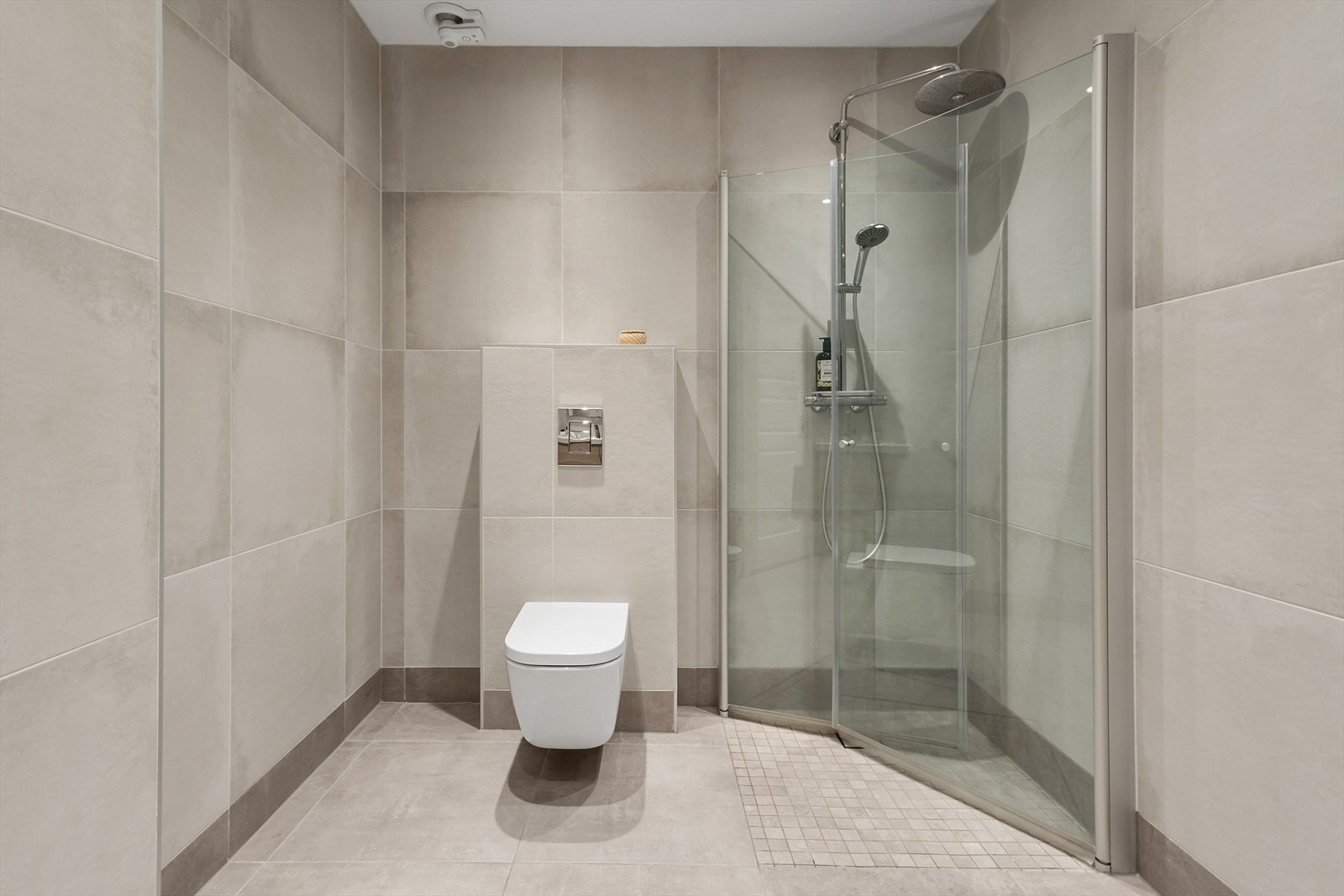 De store, delikate flisene gir et lekkert og moderne utrykk. Stor dusjnisje og god plass for oppheng av håndklær på vegg om man setter opp håndklekroker. Galleribilde